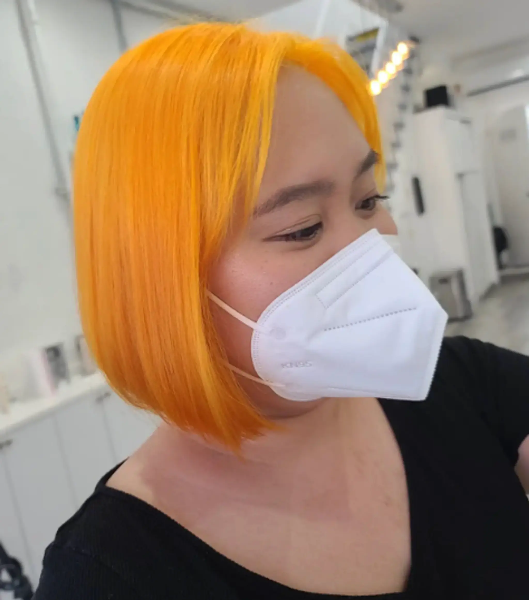 Vibrant orange medium-length bob haircut with a blunt cut and straight texture.
