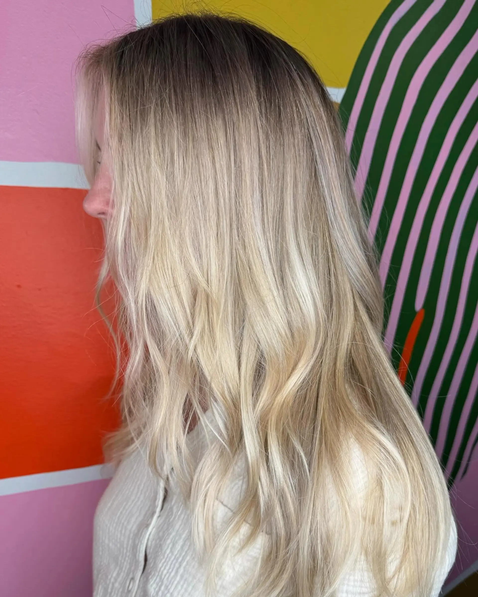 Long blonde hair styled with soft, loose waves and a seamless shadow root. 1