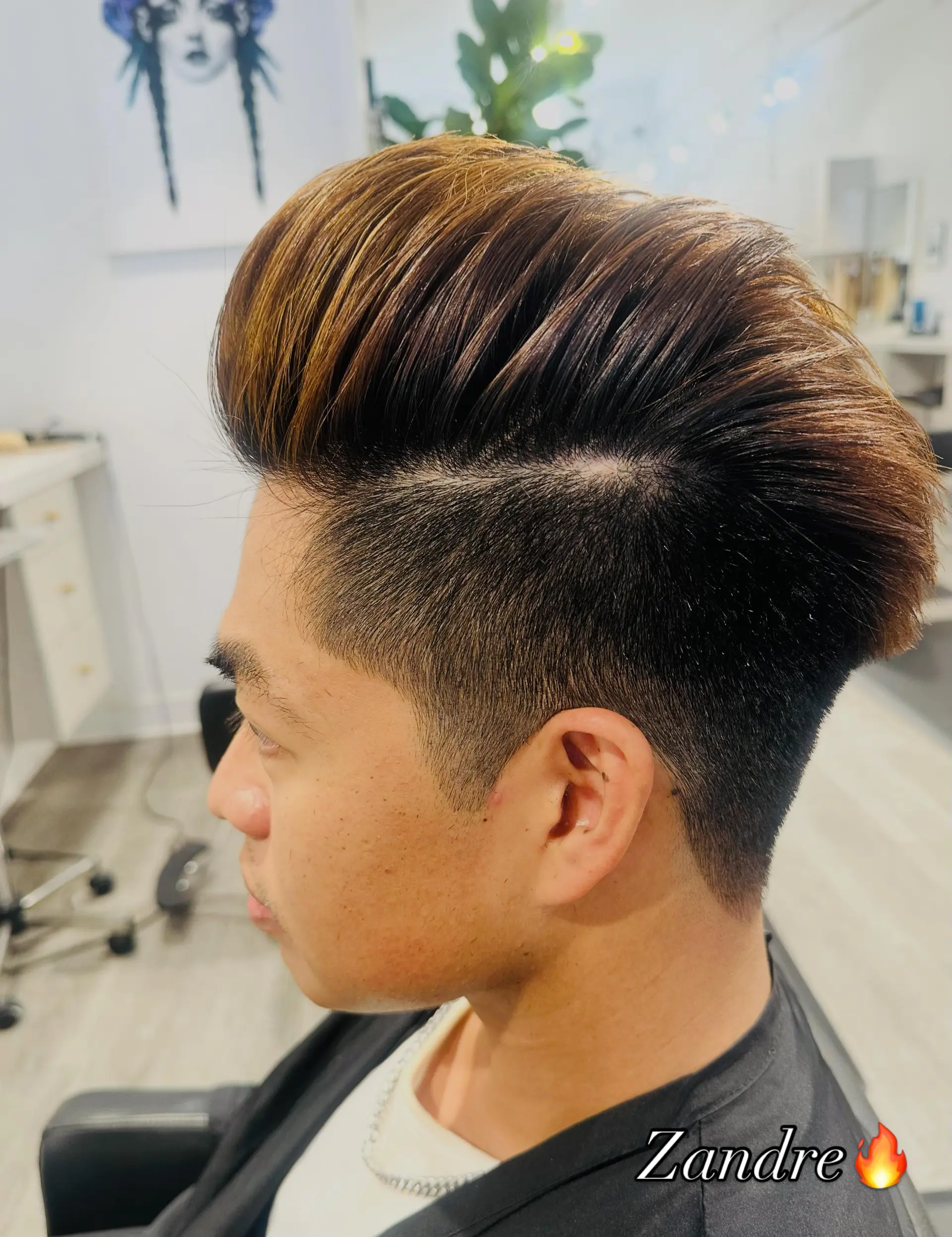 A voluminous swept-back pompadour paired with a clean mid-fade undercut and warm caramel highlights. 1