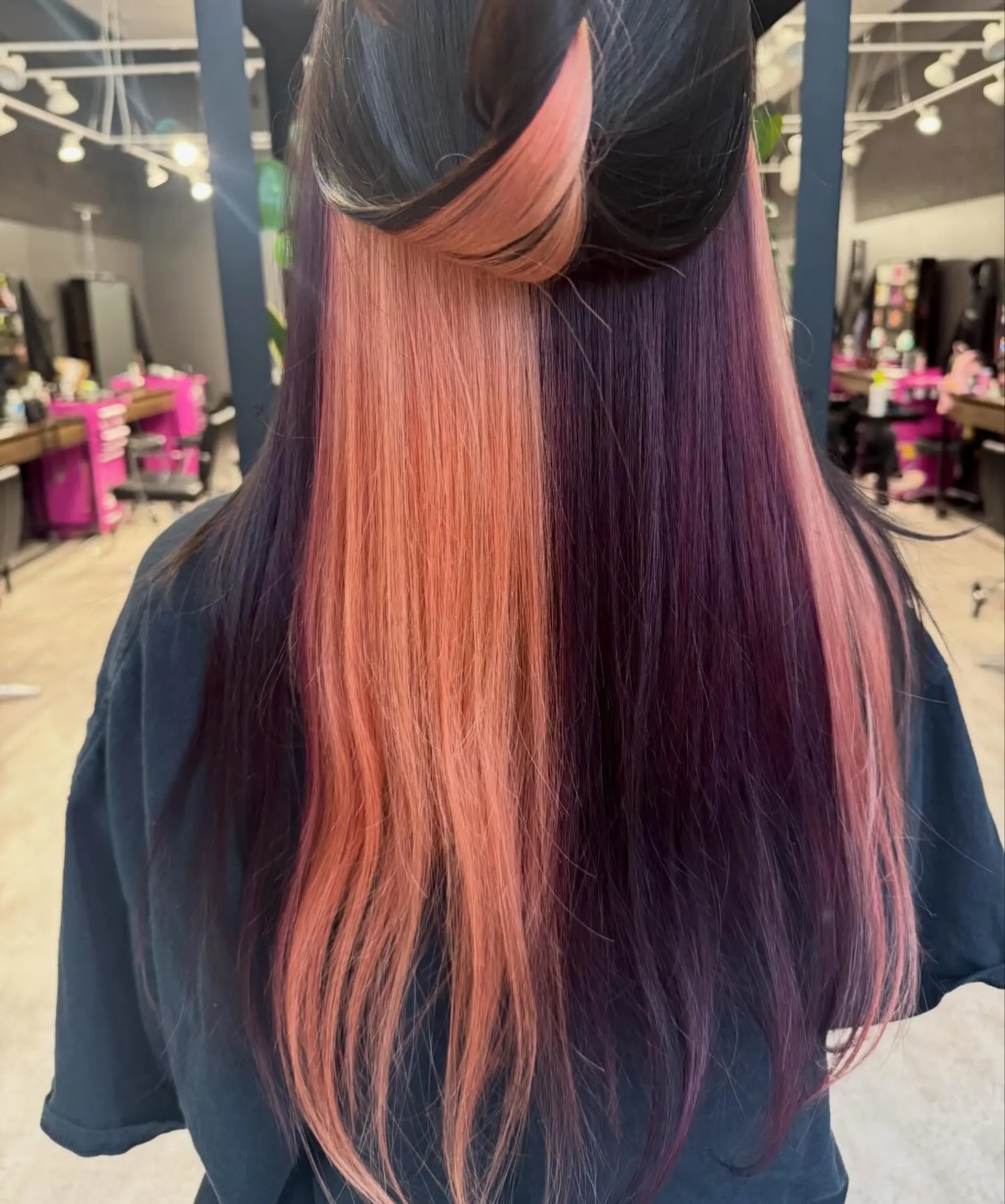 A dramatic split-dye featuring vibrant color blocks of peach and purple on long, straight hair, starting from dark natural roots. 1