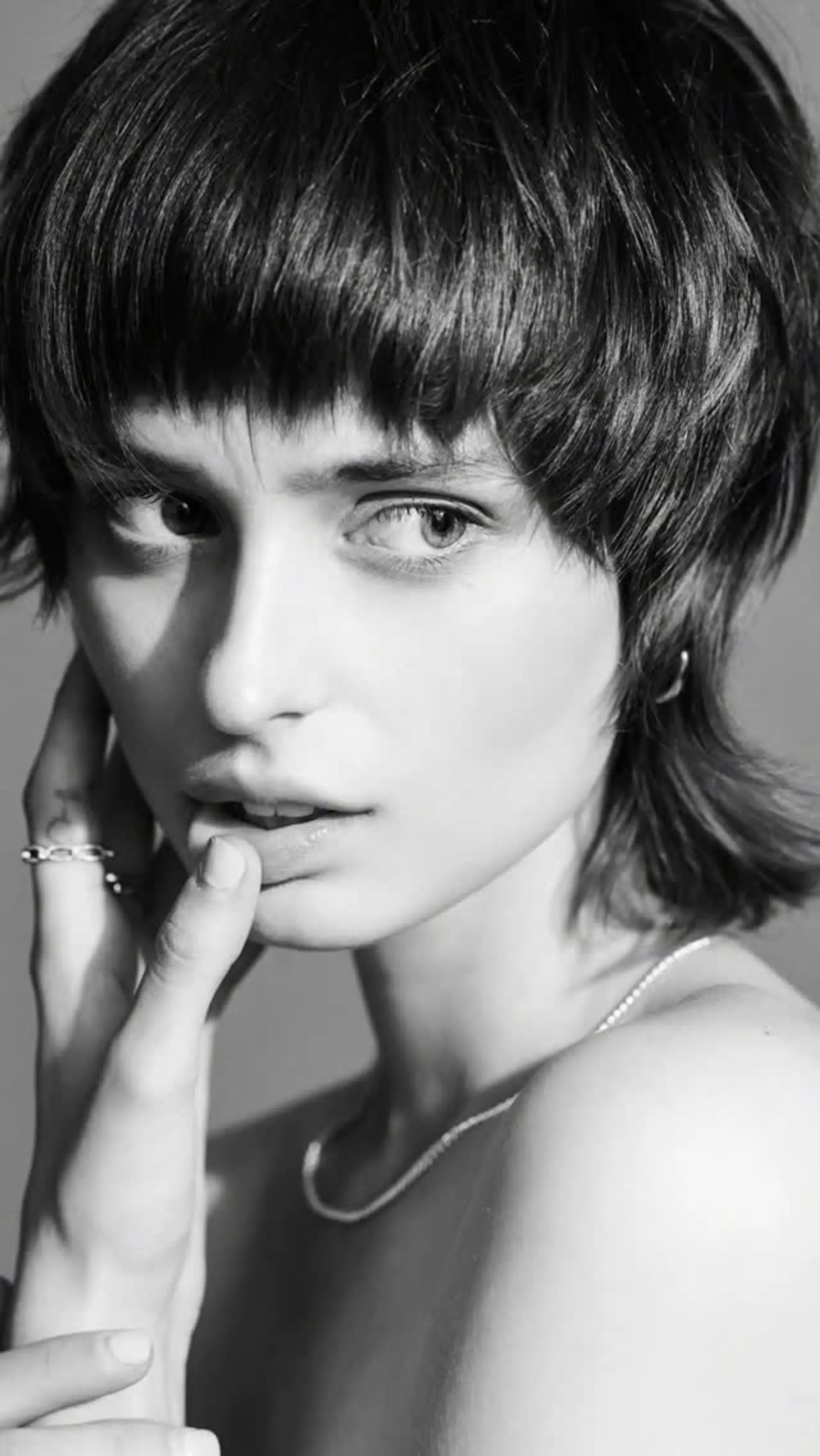 A modern textured shag mullet haircut featuring choppy eyebrow-grazing bangs, piecey layers, and tapered neck-length ends. 1
