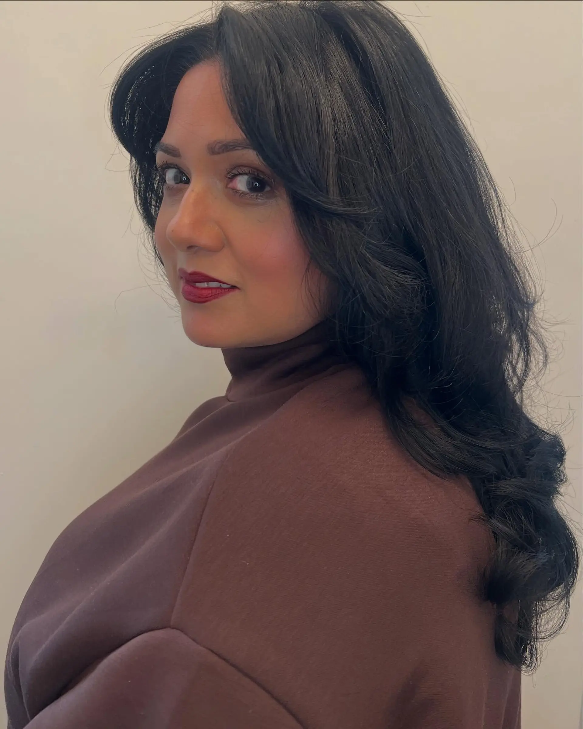 Long dark hair styled into a voluminous, bouncy blowout with soft face-framing layers and loose curls at the ends. 1