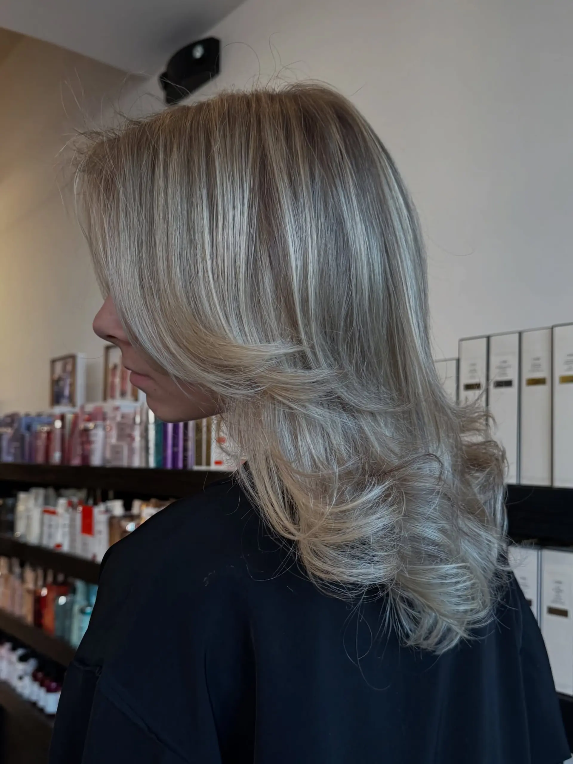 A textured blowout featuring layered ash blonde hair with soft, sweeping face-framing pieces and flipped ends. 1