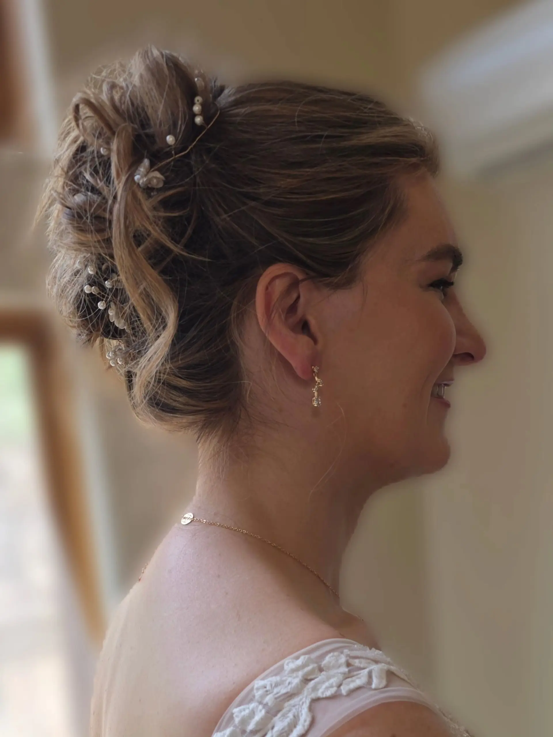 A sophisticated high bridal updo with textured curls and waves, accented with delicate pearl floral hairpins. 1