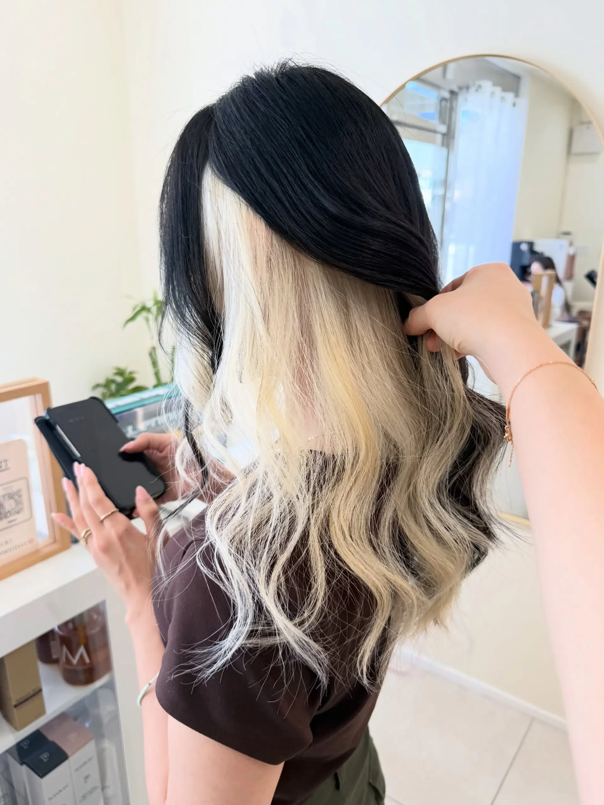 Long soft wavy black hair revealing high-contrast platinum blonde peekaboo underlights underneath. 1