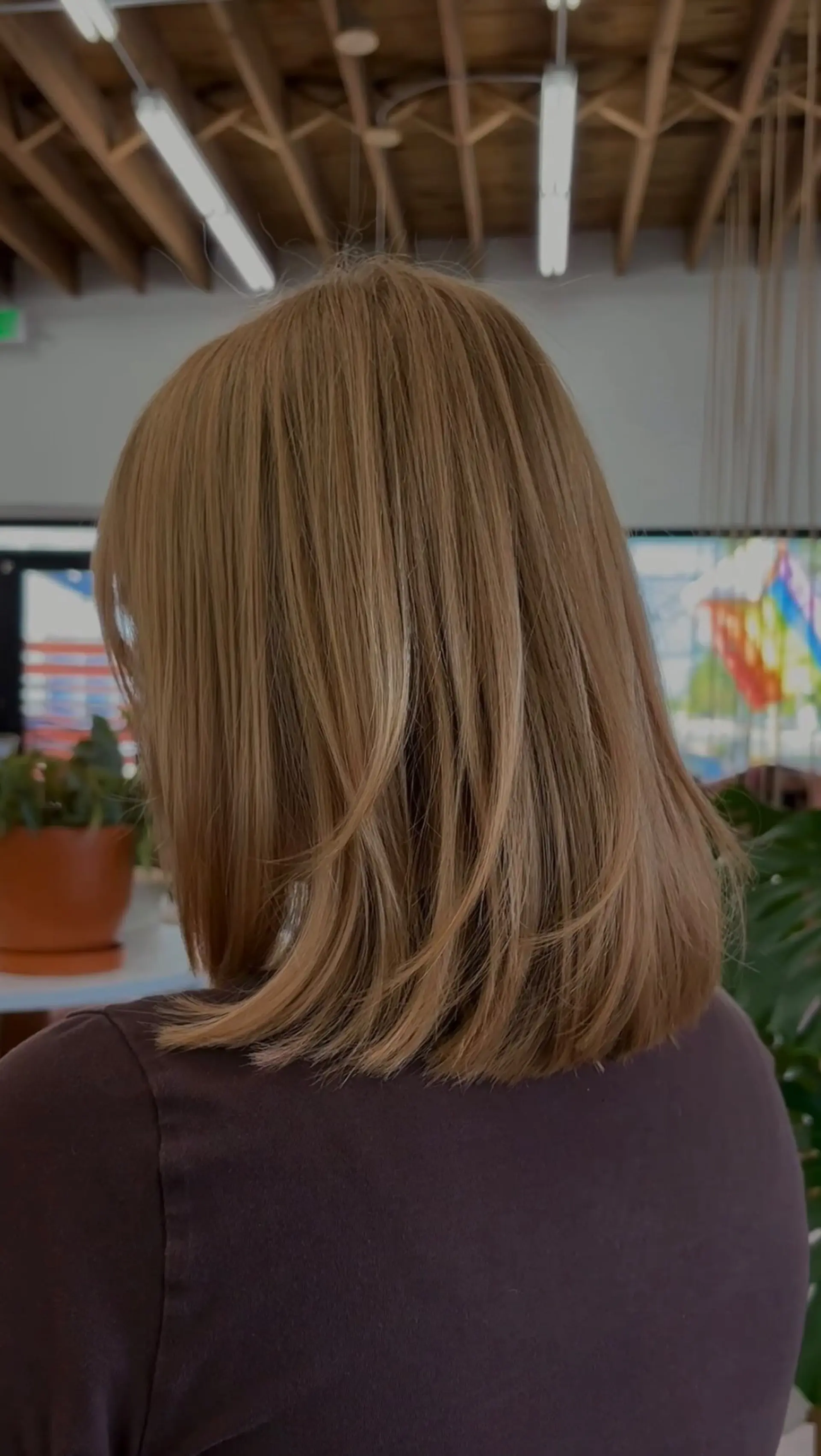 A textured shoulder-length lob cut with soft interior layers, styled straight with gentle movement in a warm honey blonde tone. 1