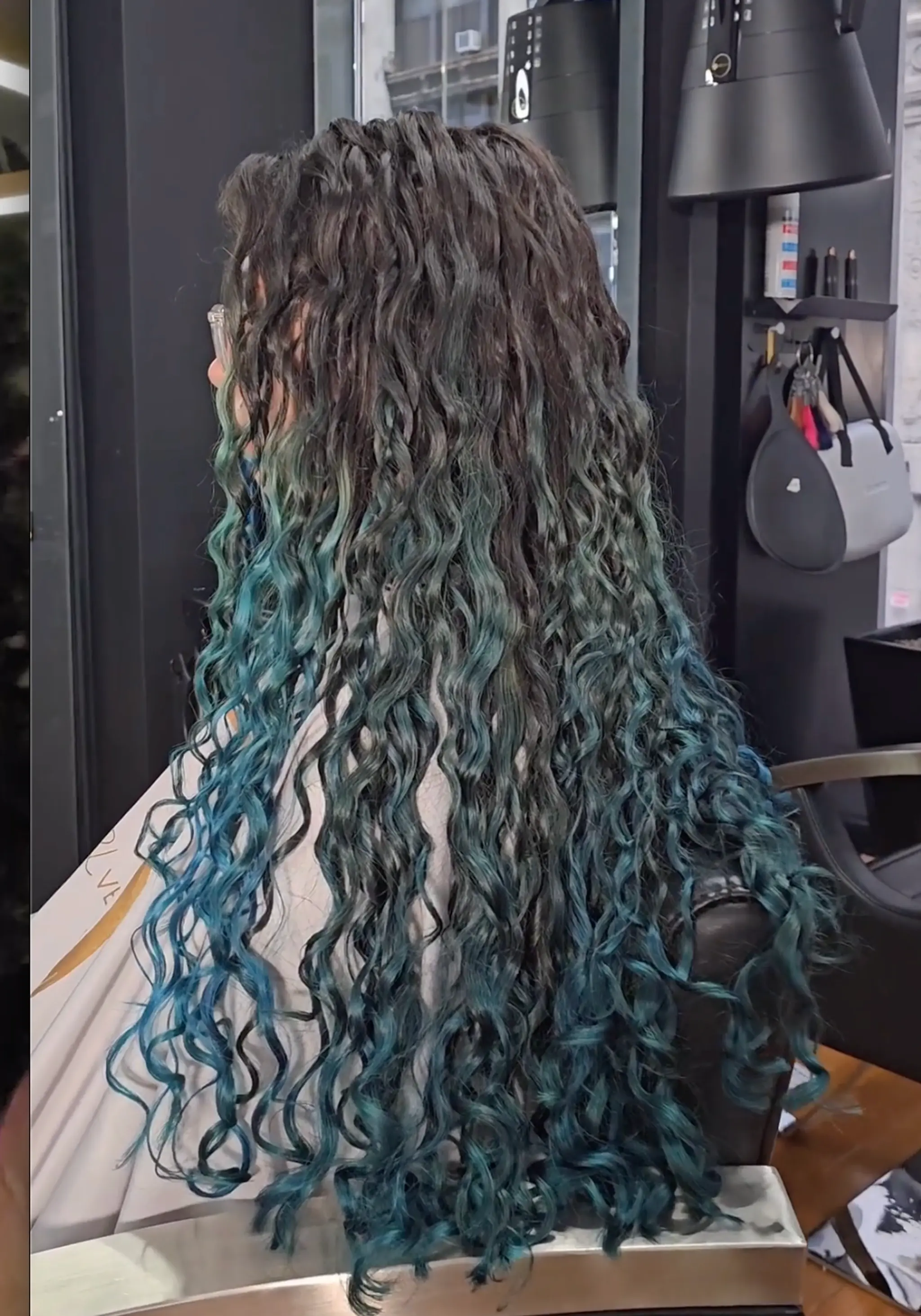 Very long, curly hair with an ombre effect transitioning from dark brown to turquoise and blue, featuring voluminous, well-defined curls.