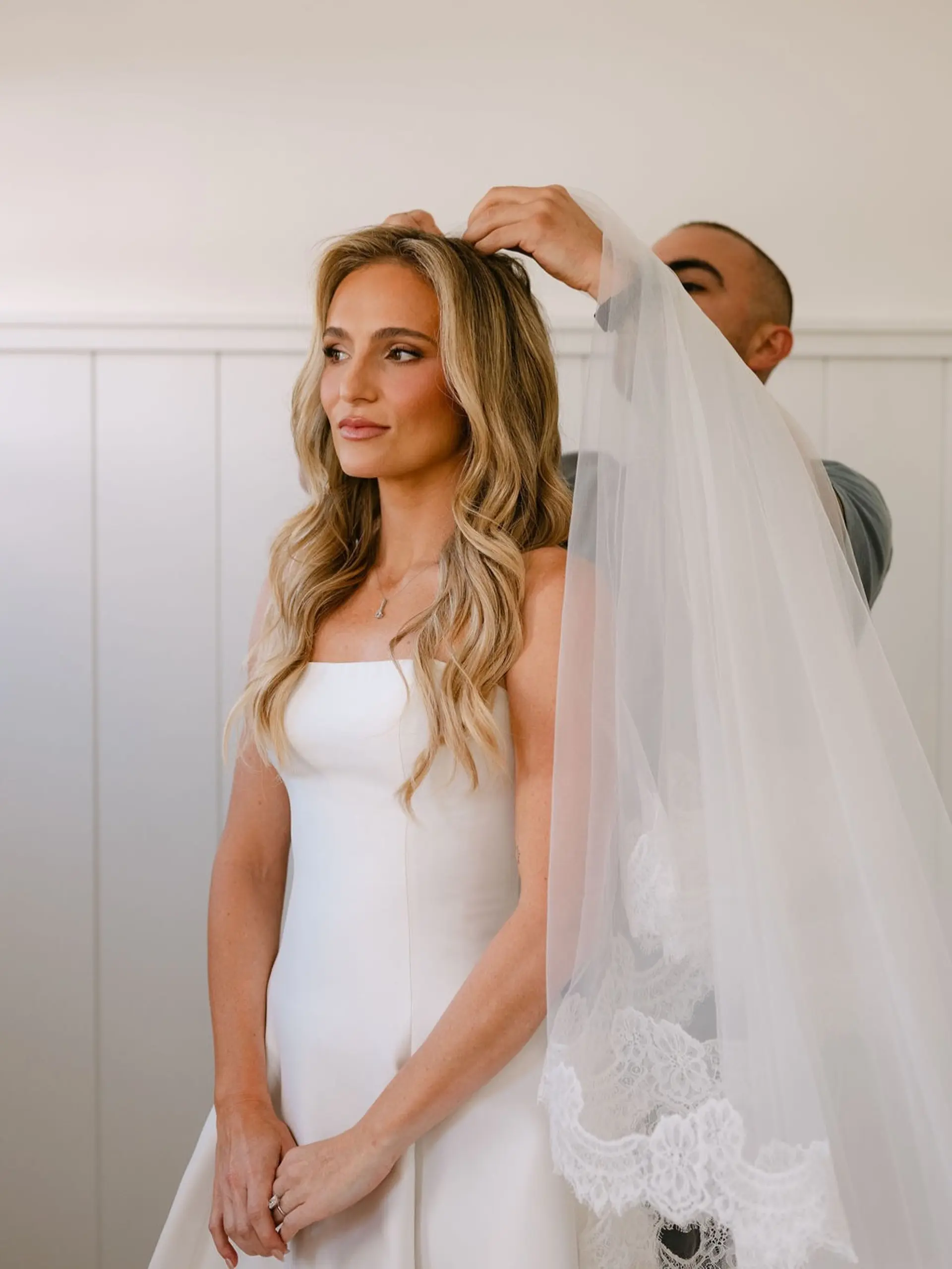 Long wavy bridal hair styled with dimensional blonde balayage highlights and a lace veil. 1