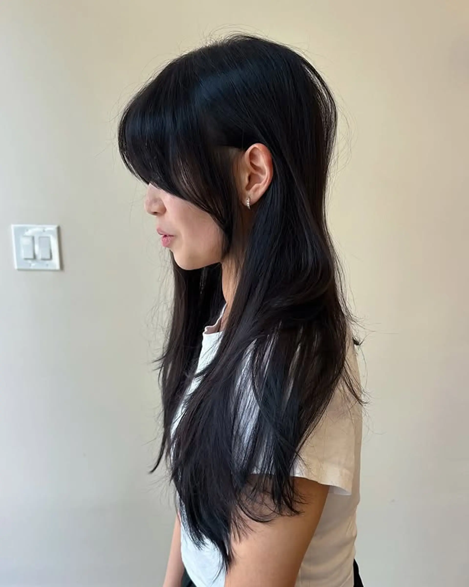 This hairstyle features curtain bangs and long layers for a modern, face-framing effect. 1