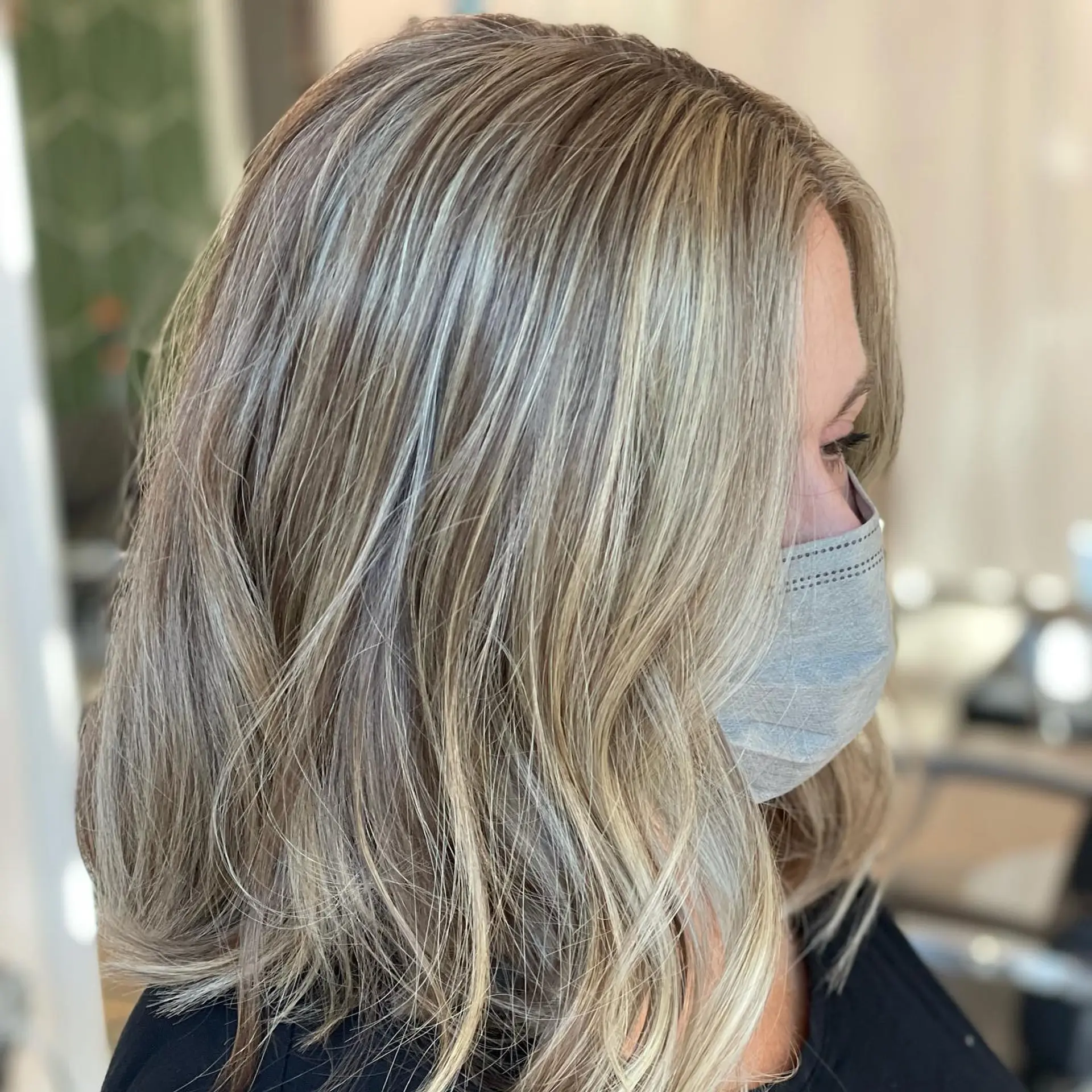 A collarbone-length lob haircut styled with subtle, lived-in waves and multi-dimensional blonde highlights. 1