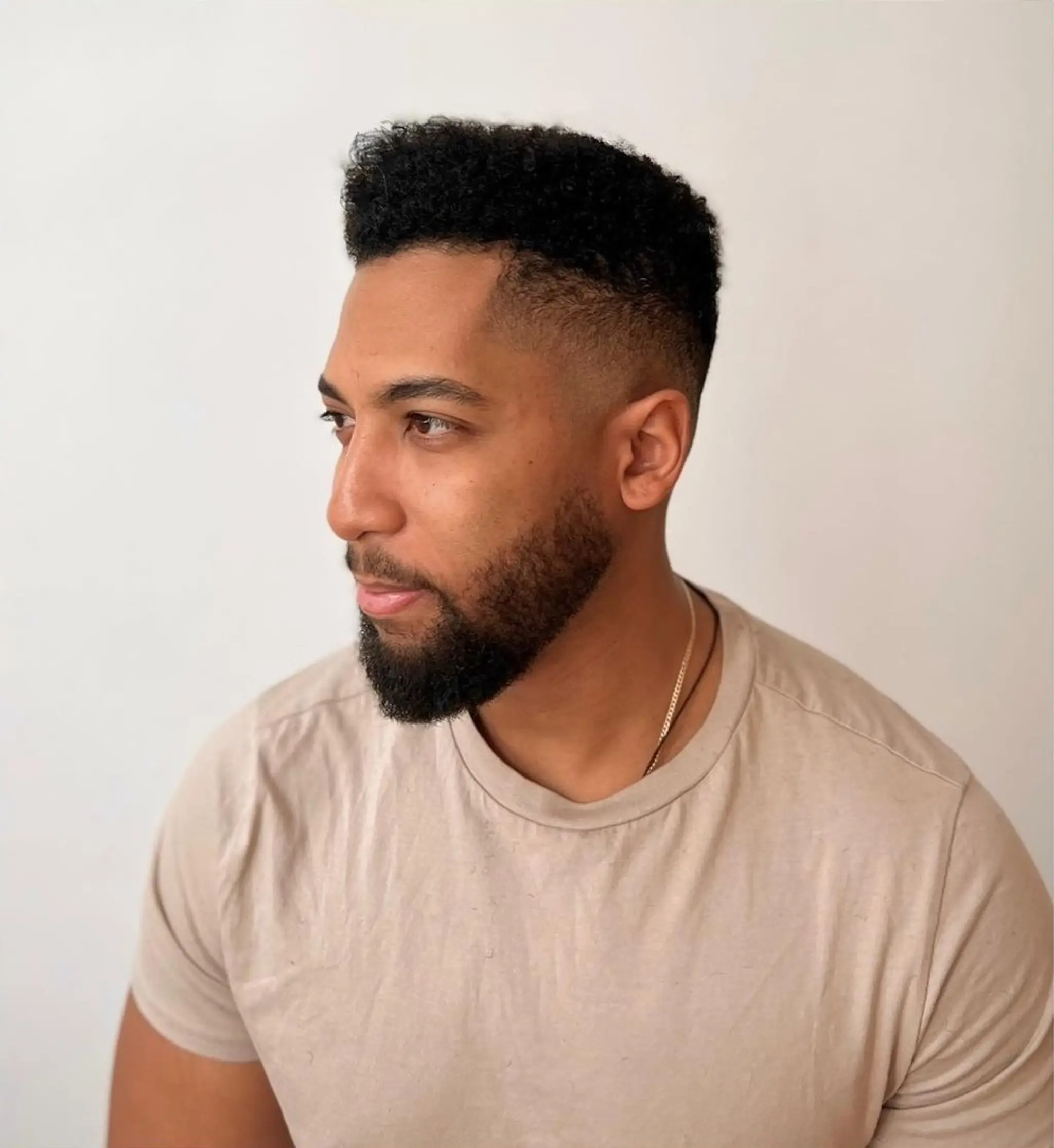 Short curly hairstyle with a fade, featuring dense, textured curls on top and smoothly faded sides, complemented by a neatly groomed beard. ✂️@sdr______