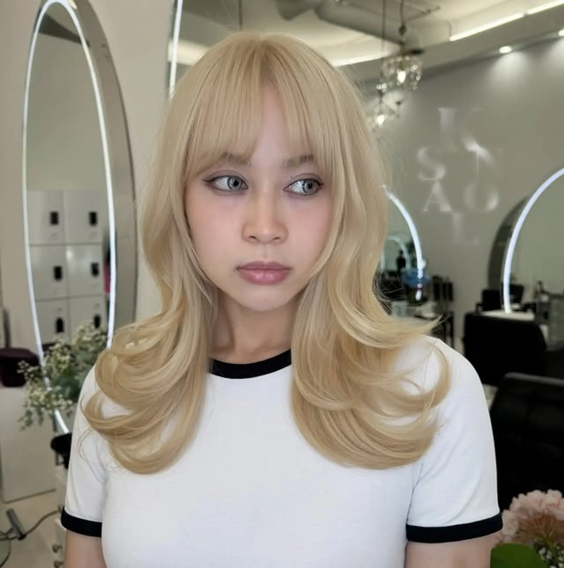 A wavy, medium-length hairstyle with soft Bardot waves and face-framing curtain bangs. 1