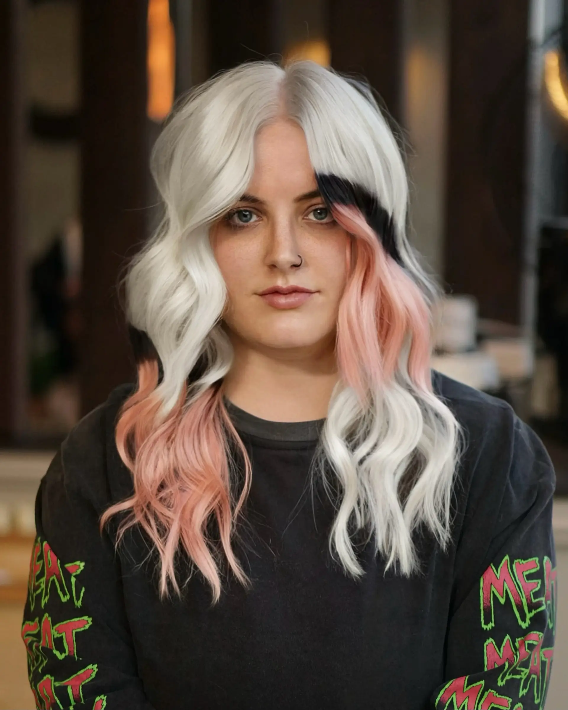 Medium-length icy platinum blonde styled into soft, defined waves featuring high-contrast color blocking with pastel pink and deep black panels. 1
