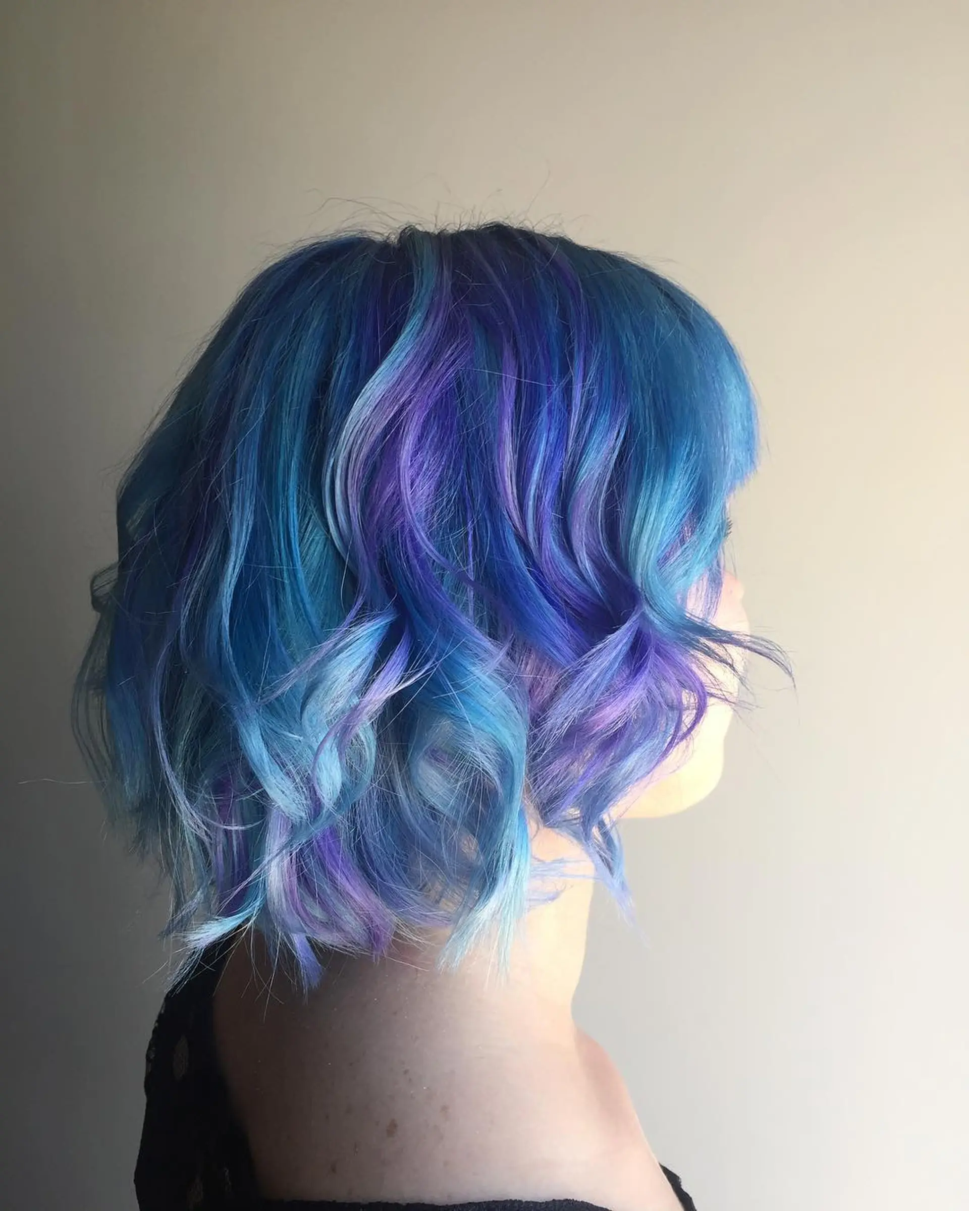 A short wavy bob with a vibrant blend of blue, purple, and lavender hues. 1