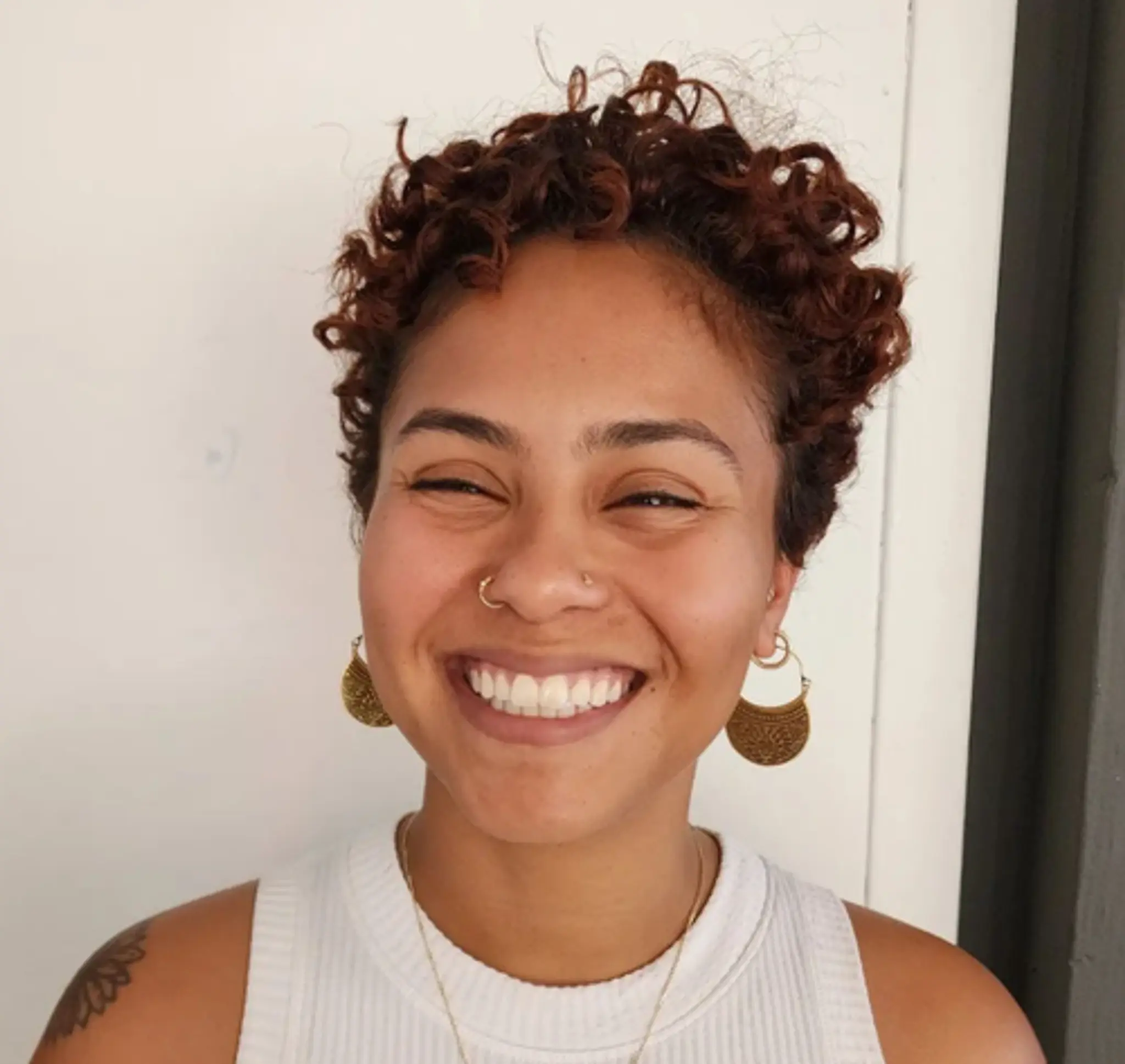 Short, light brown curly hair with natural texture and voluminous curls.