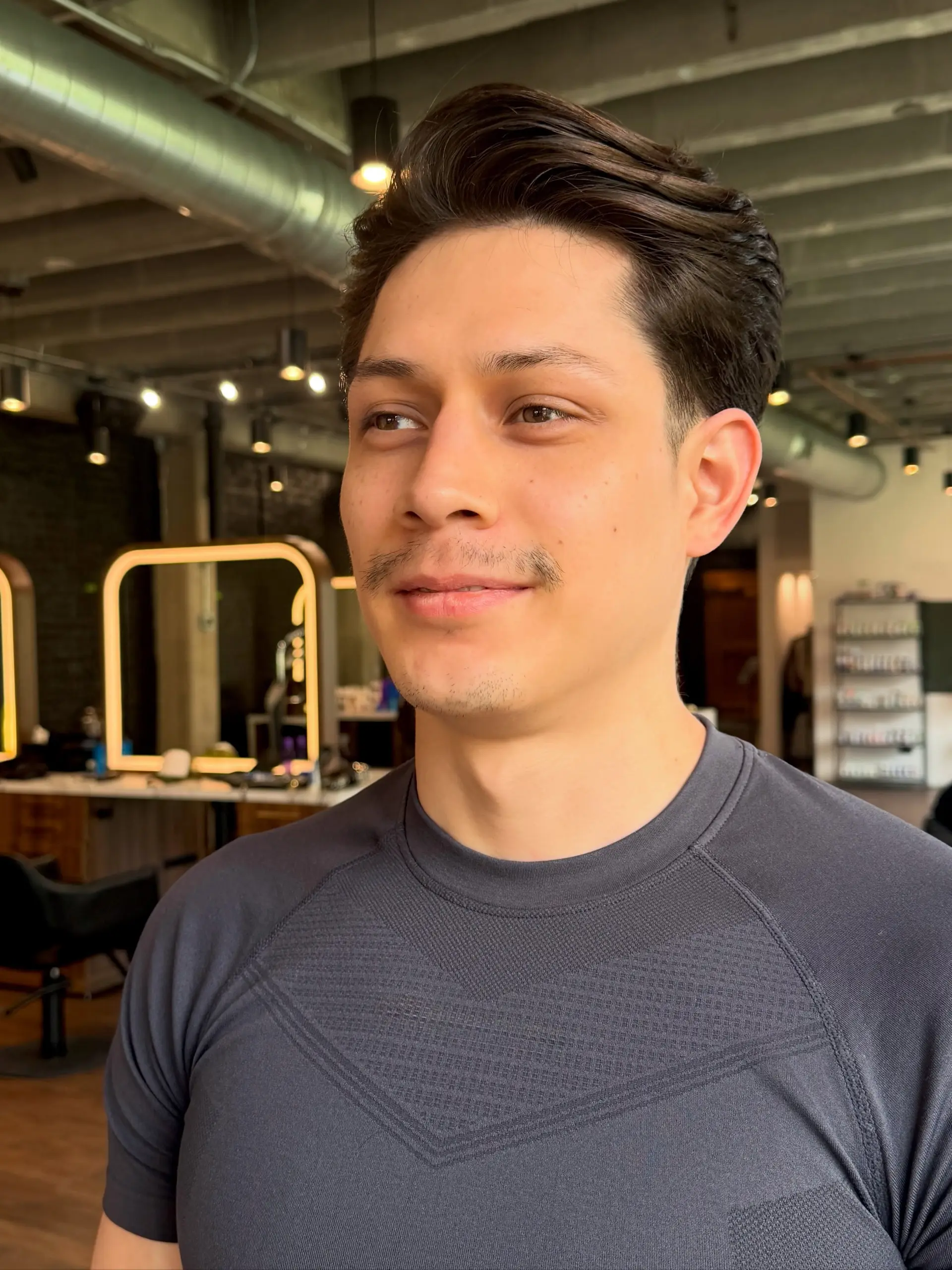 A modern men's haircut featuring neatly tapered sides and a textured, swept-back top with soft volume. 1