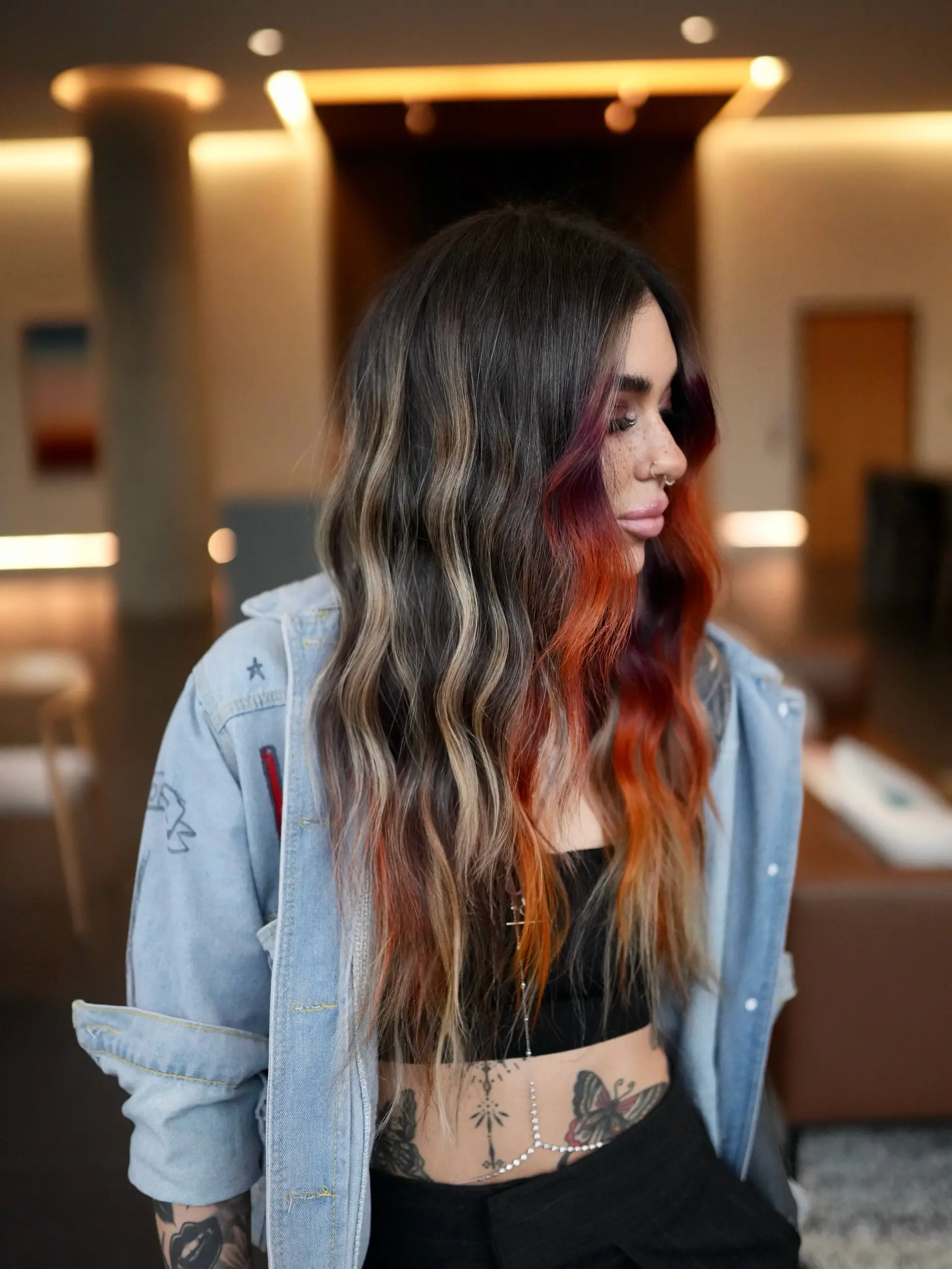 Long wavy dark brunette hair featuring cool ash-blonde balayage ribbons paired with a fiery sunset-colored face-framing money piece in shades of orchid, coral, and yellow. 1
