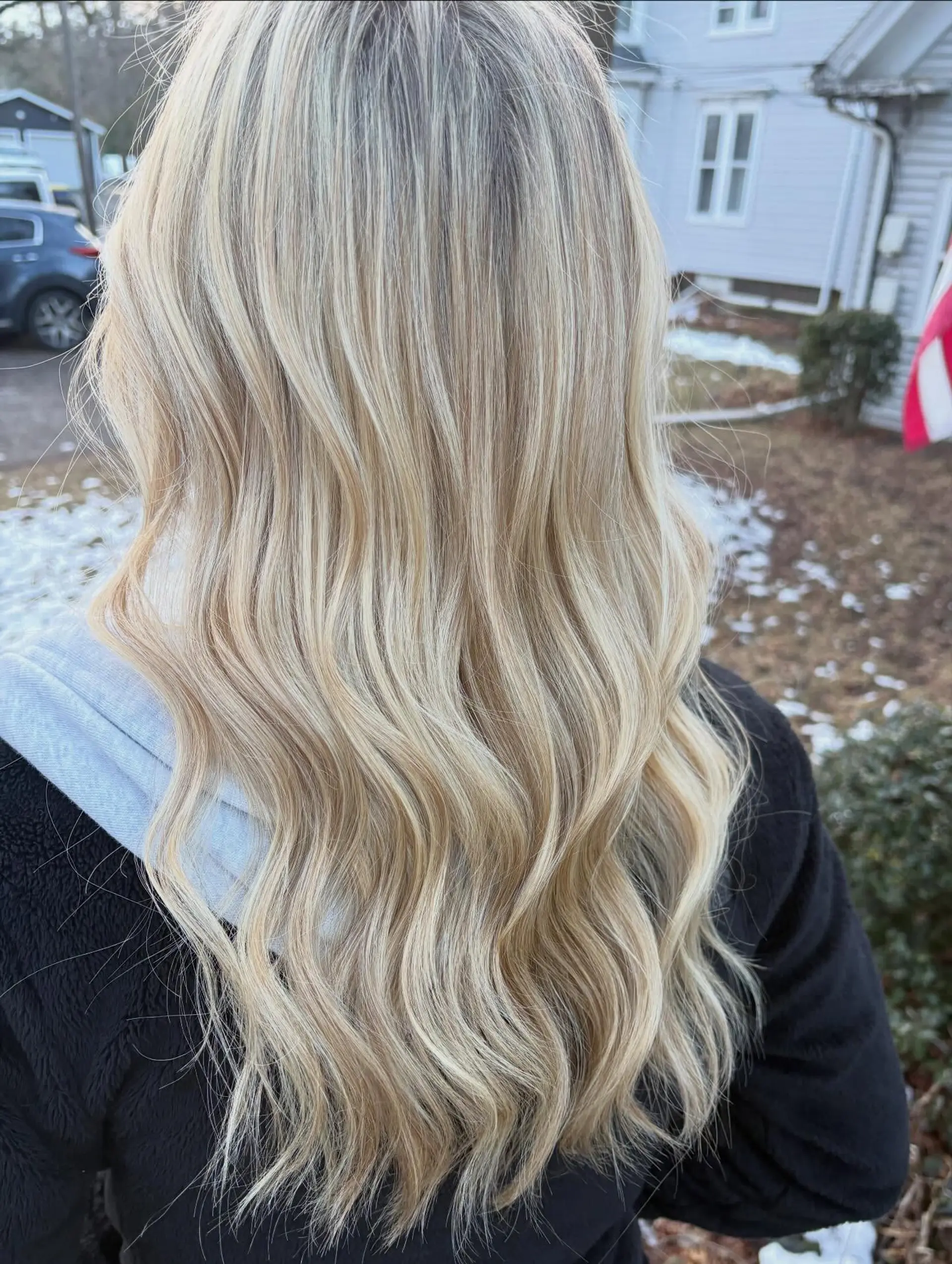 Long dimensional blonde hair styled into soft, flowing beach waves. 1