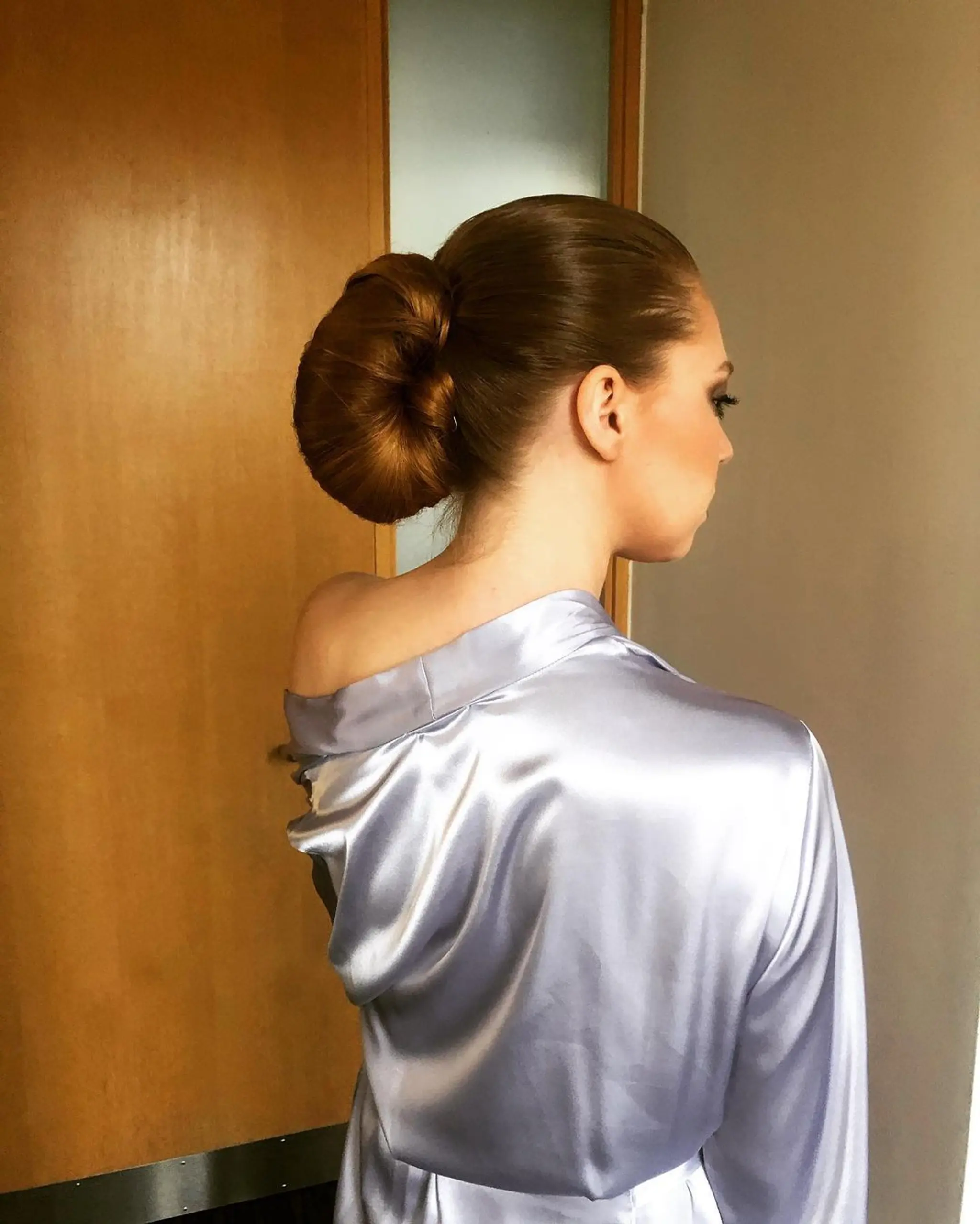 An elegant chignon with straight, long light brown hair styled into a low, polished bun. 1