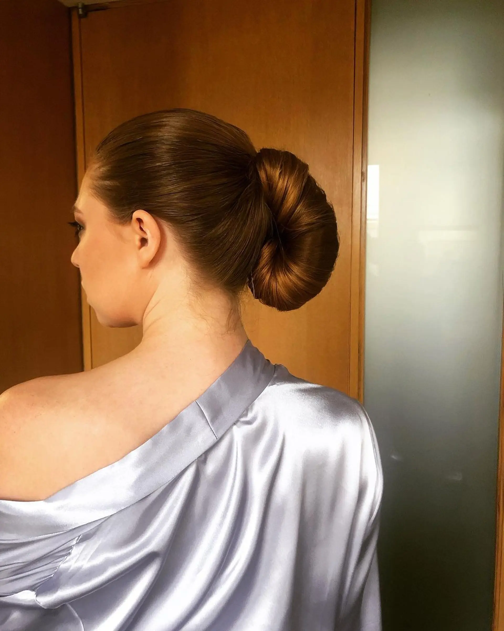 An elegant chignon with straight, long light brown hair styled into a low, polished bun. 2