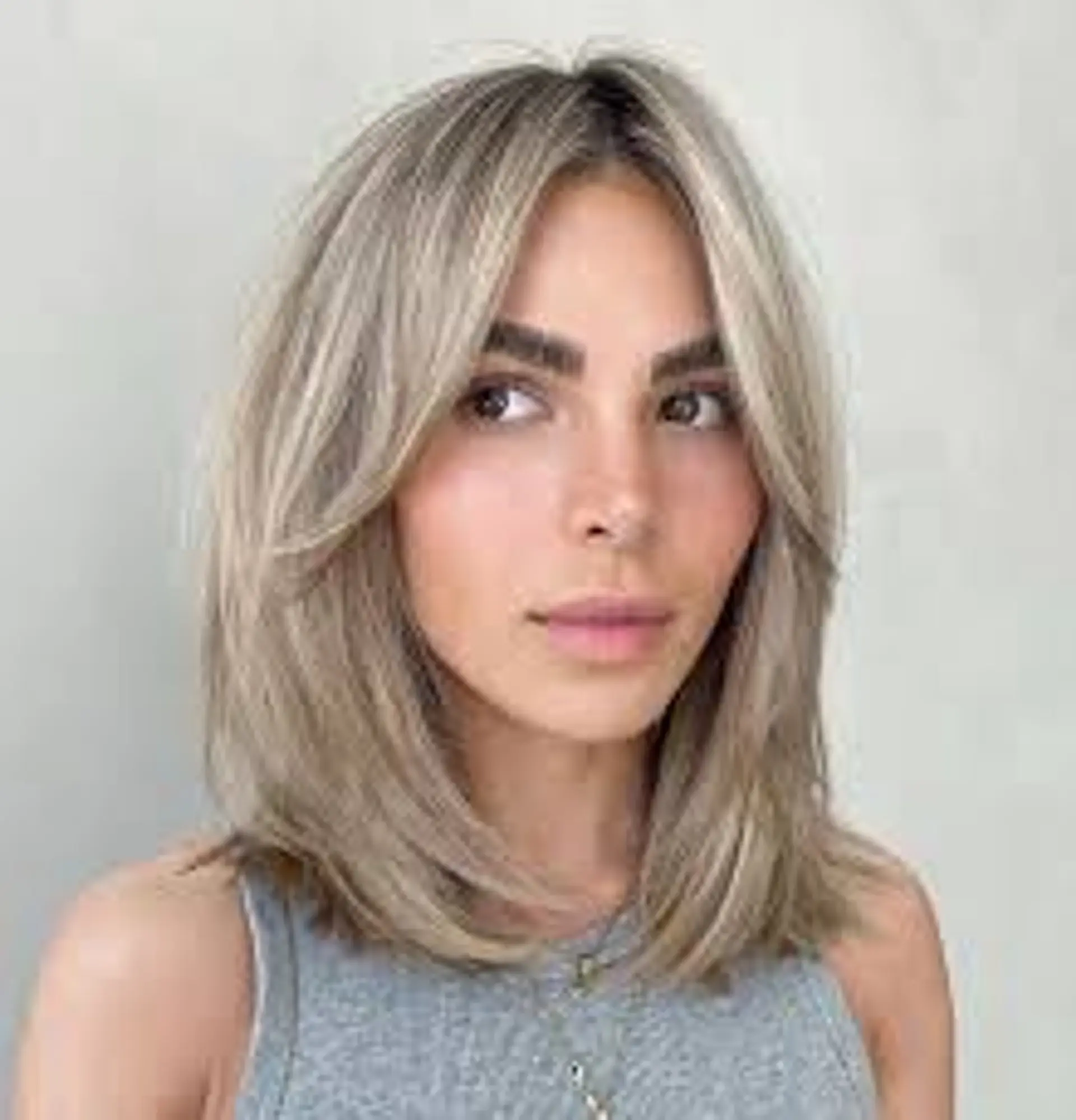 Medium length wavy bob with face-framing layers and a side part, accented by ash blonde and platinum highlights for a dimensional look. 1