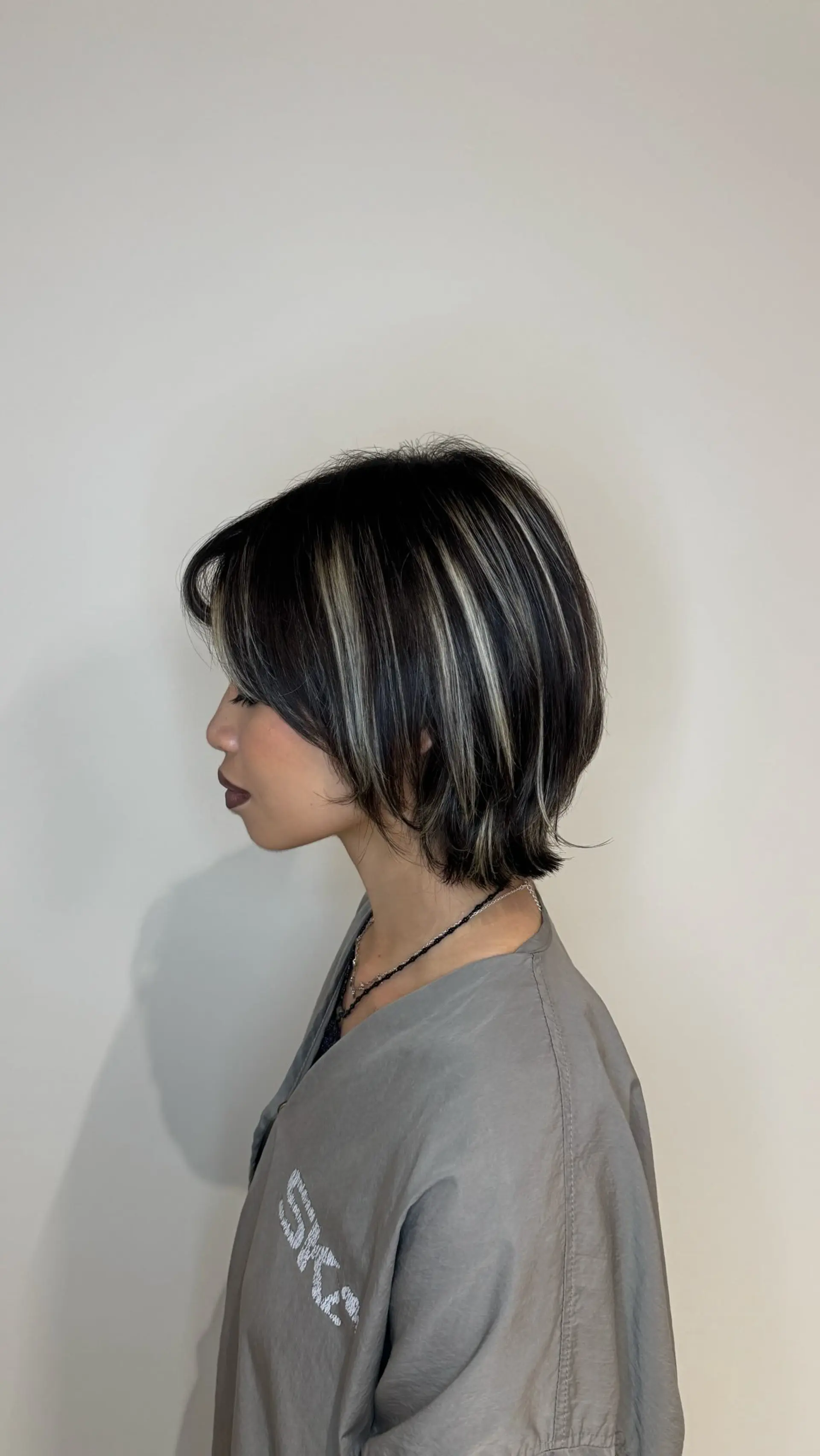 A textured short bixie haircut with defined platinum and ash blonde highlights over a dark base. 1