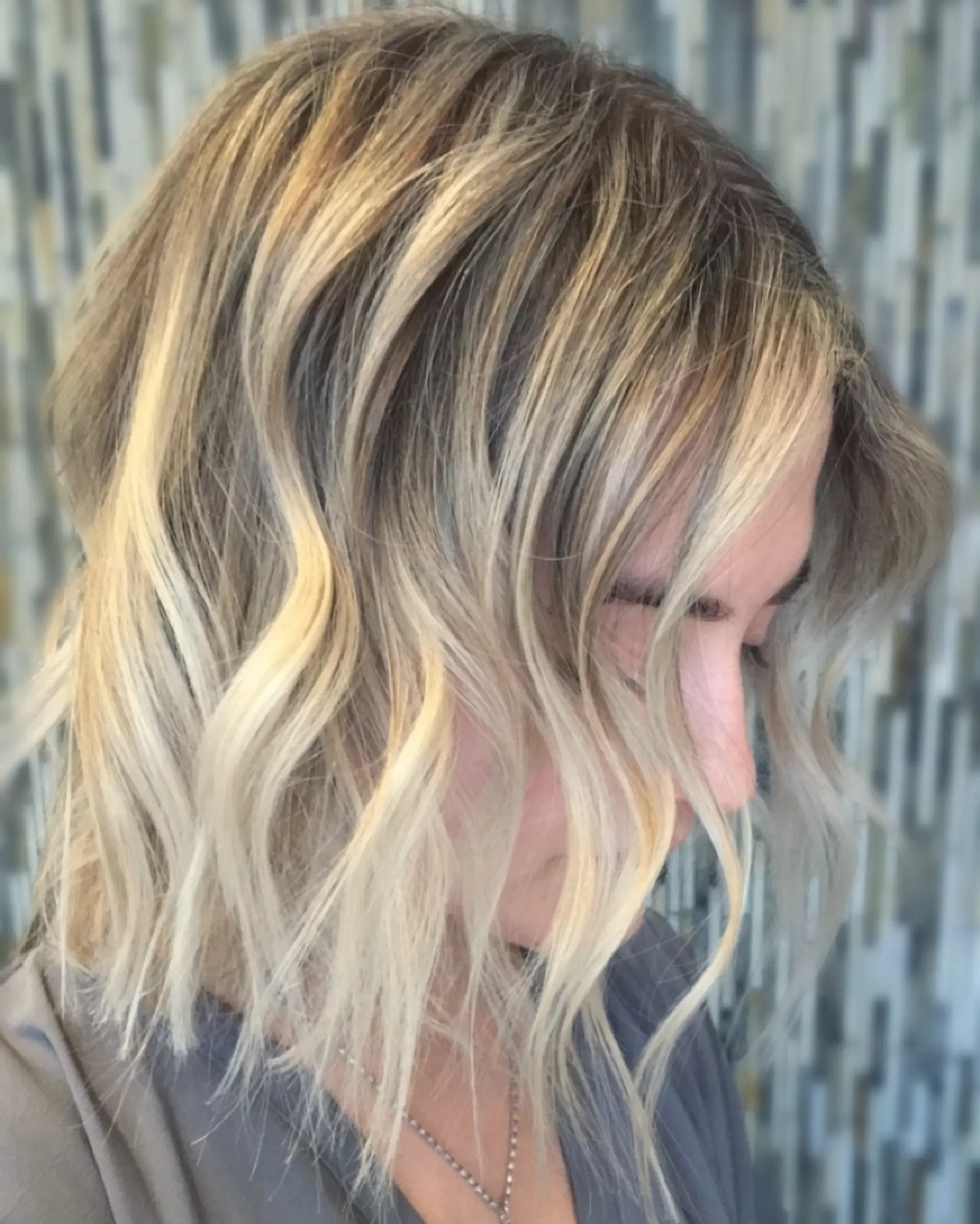 A collarbone-length textured lob styled in effortless, undone waves with bright blonde highlights. 1