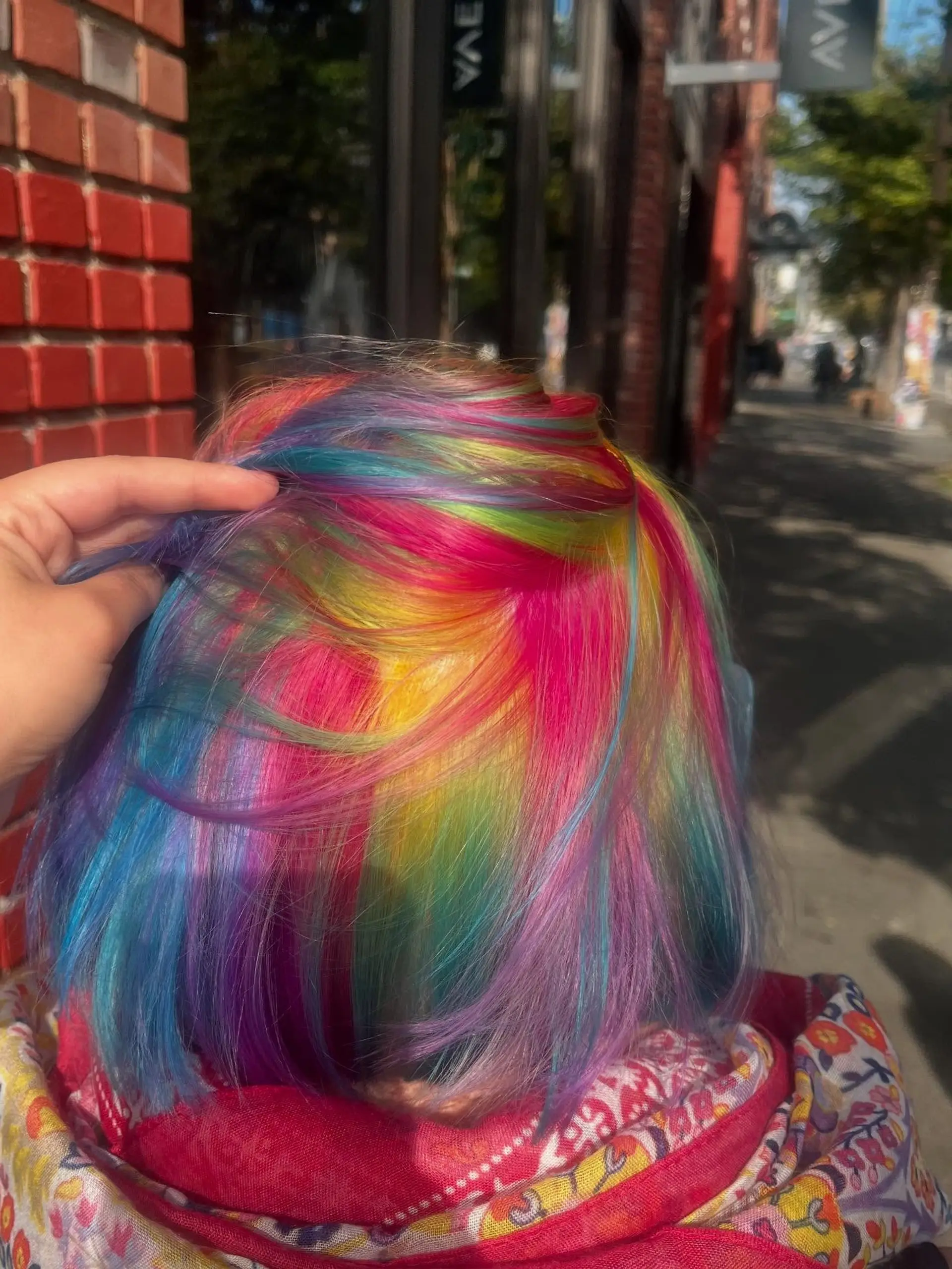 A vibrant short bob dyed with a multi-tonal rainbow prism effect featuring vivid pink, yellow, blue, purple, and green shades. 1