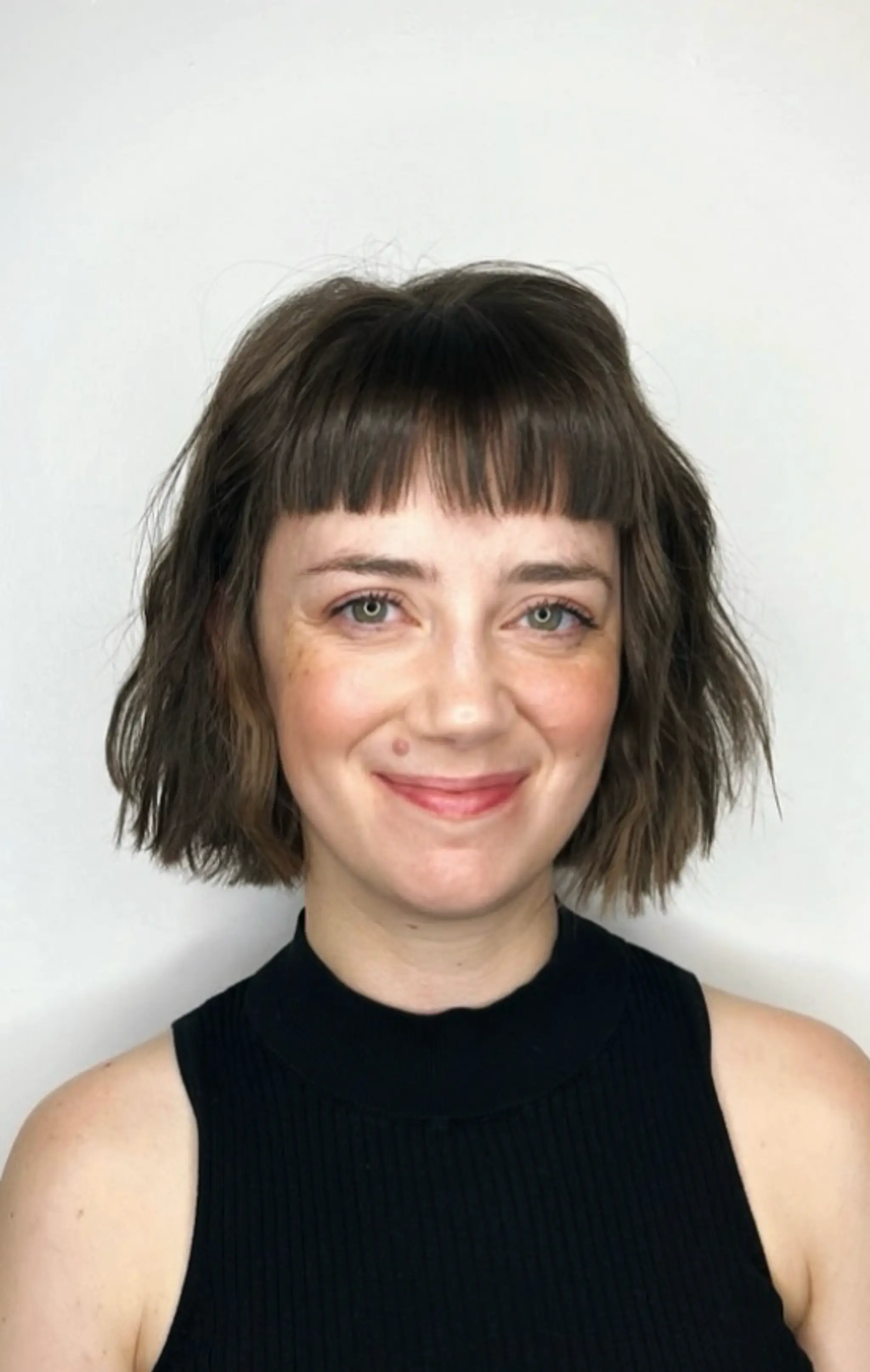 A chic, tousled bob cut with blunt bangs, featuring wavy and textured hair in a short length, predominantly brown in color.

Cut and style by @juliamannino_hair
