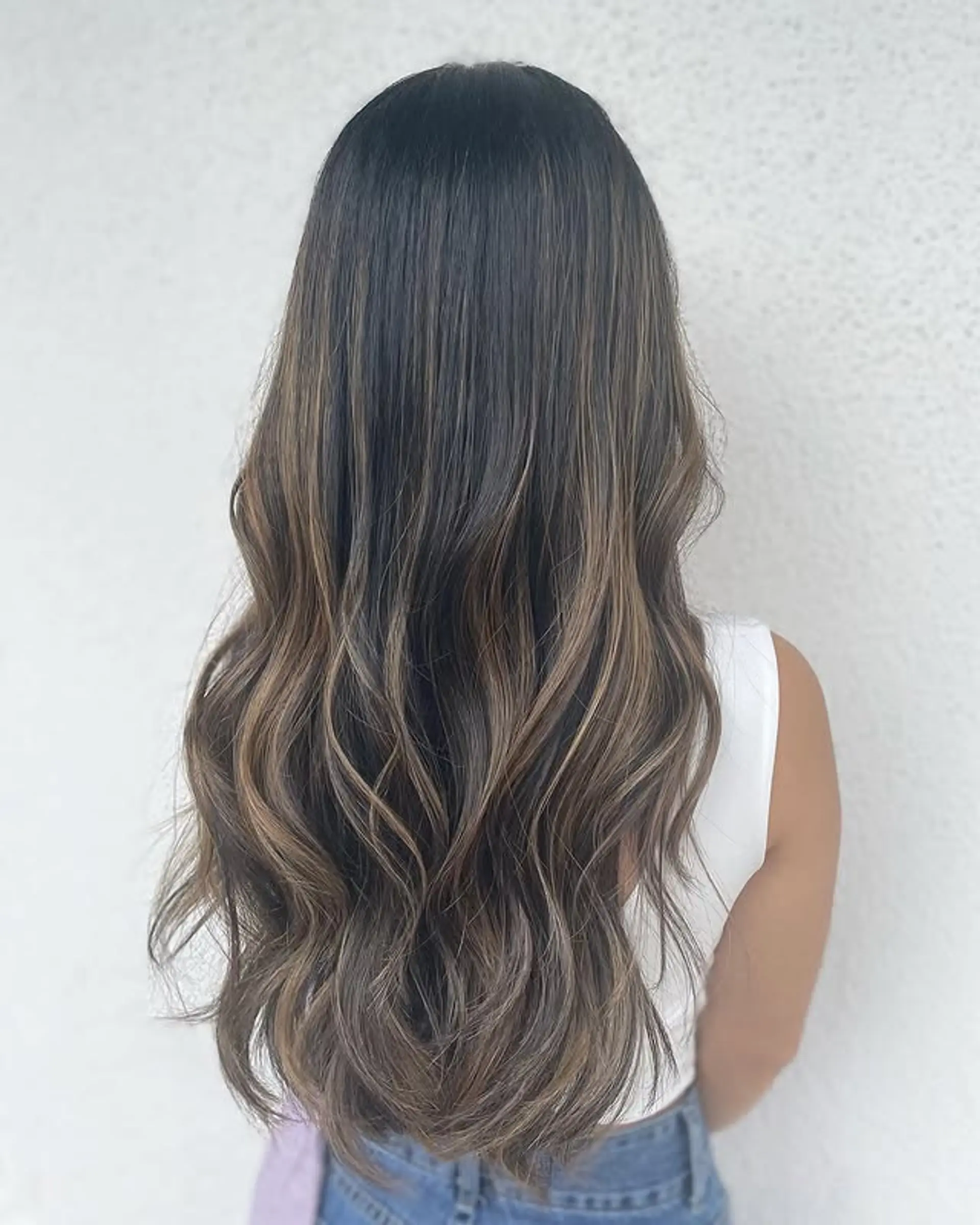 Long, wavy hair with dark brown roots and caramel highlights. 1
