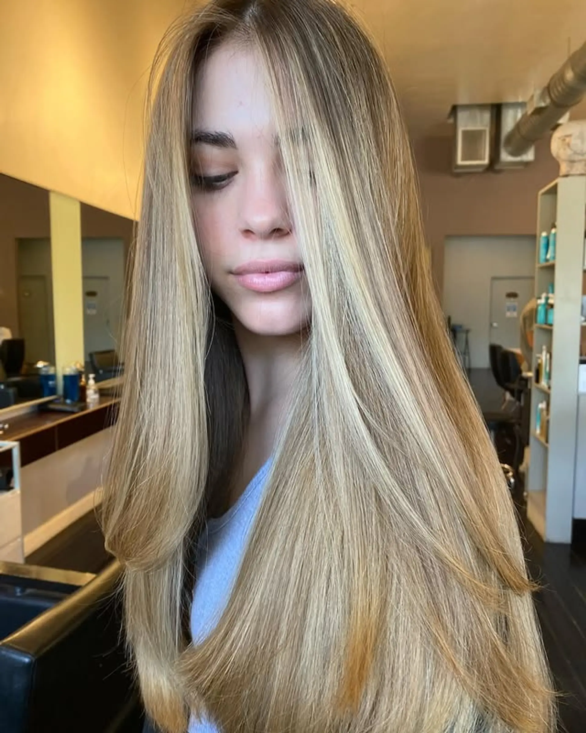Long, layered hairstyle with golden blonde highlights and face-framing layers. 1