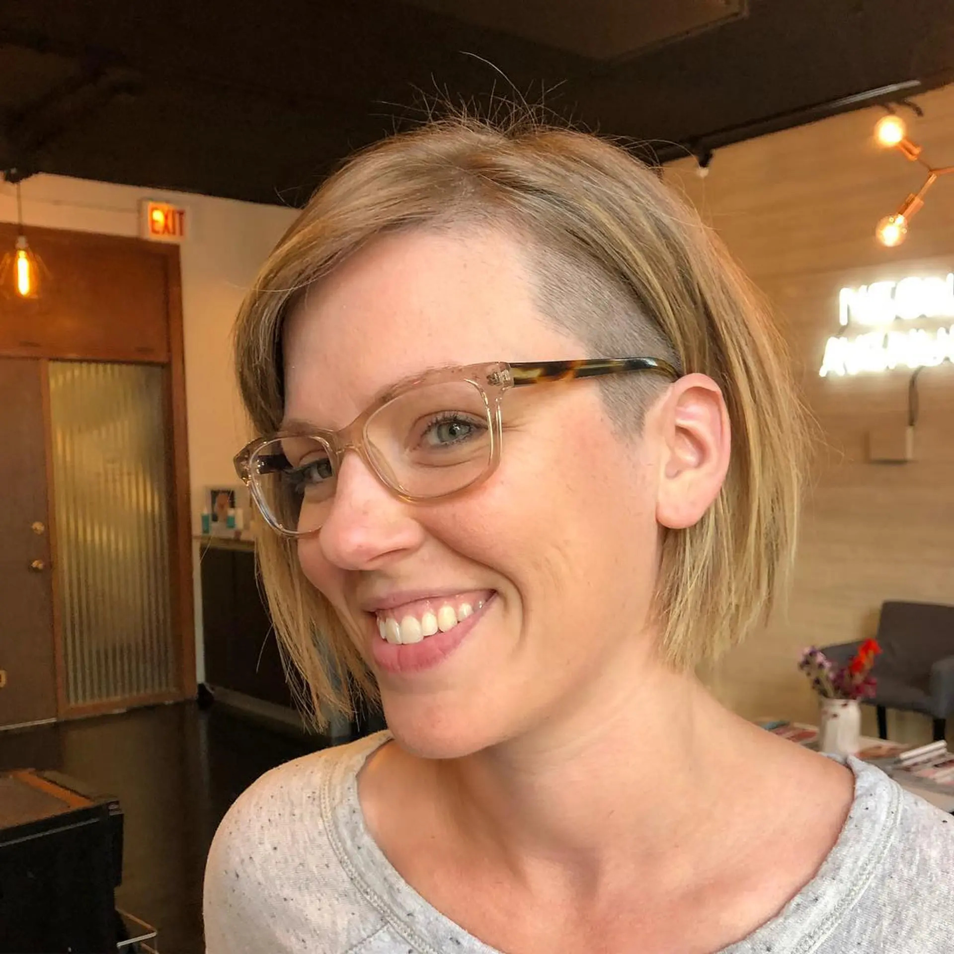 A straight chin-length blonde bob featuring a contrasting shaved side undercut above the ear. 1