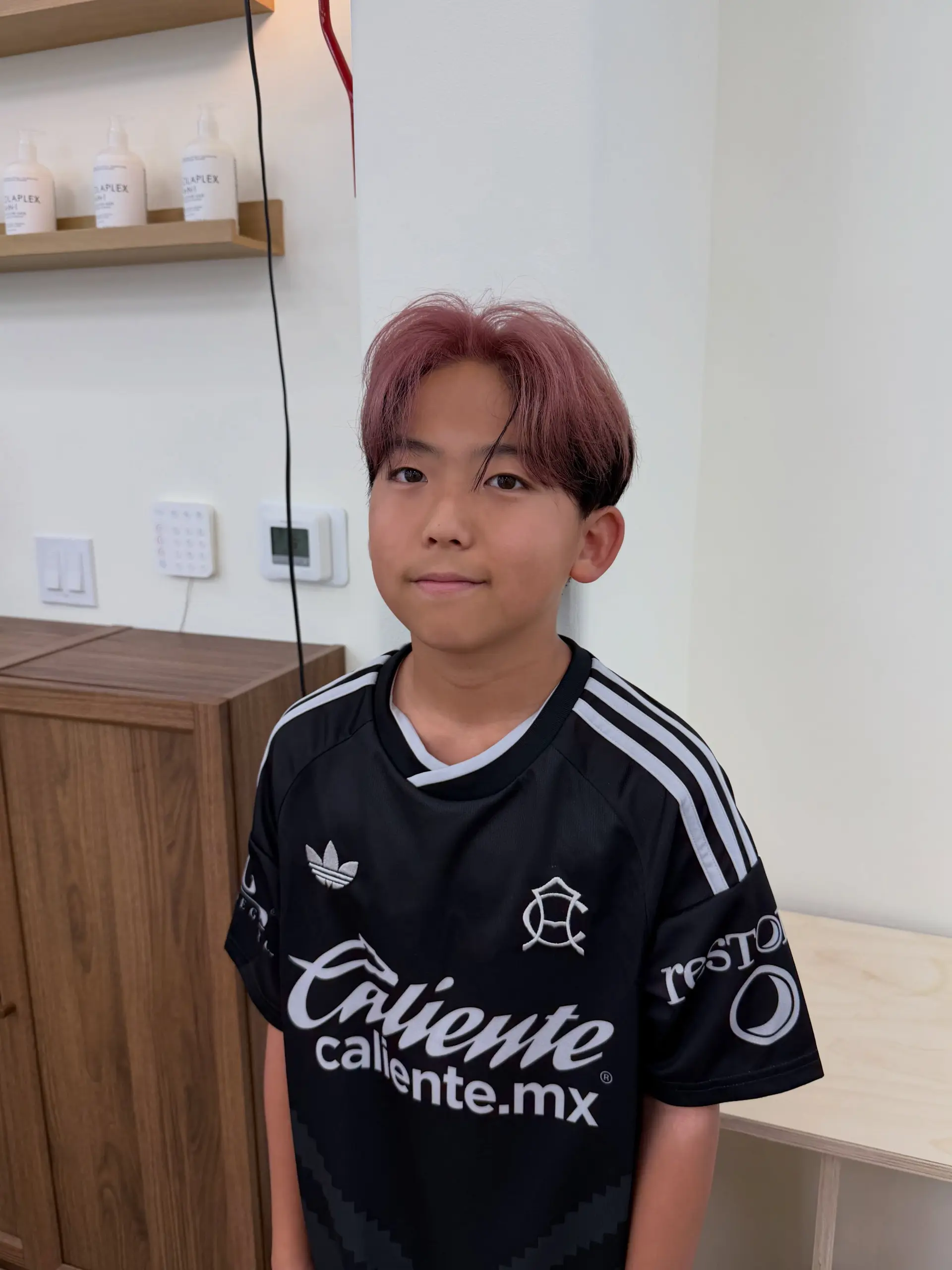 A short men's cut styled with center-parted curtain bangs and dyed a soft dusty rose pink. 1