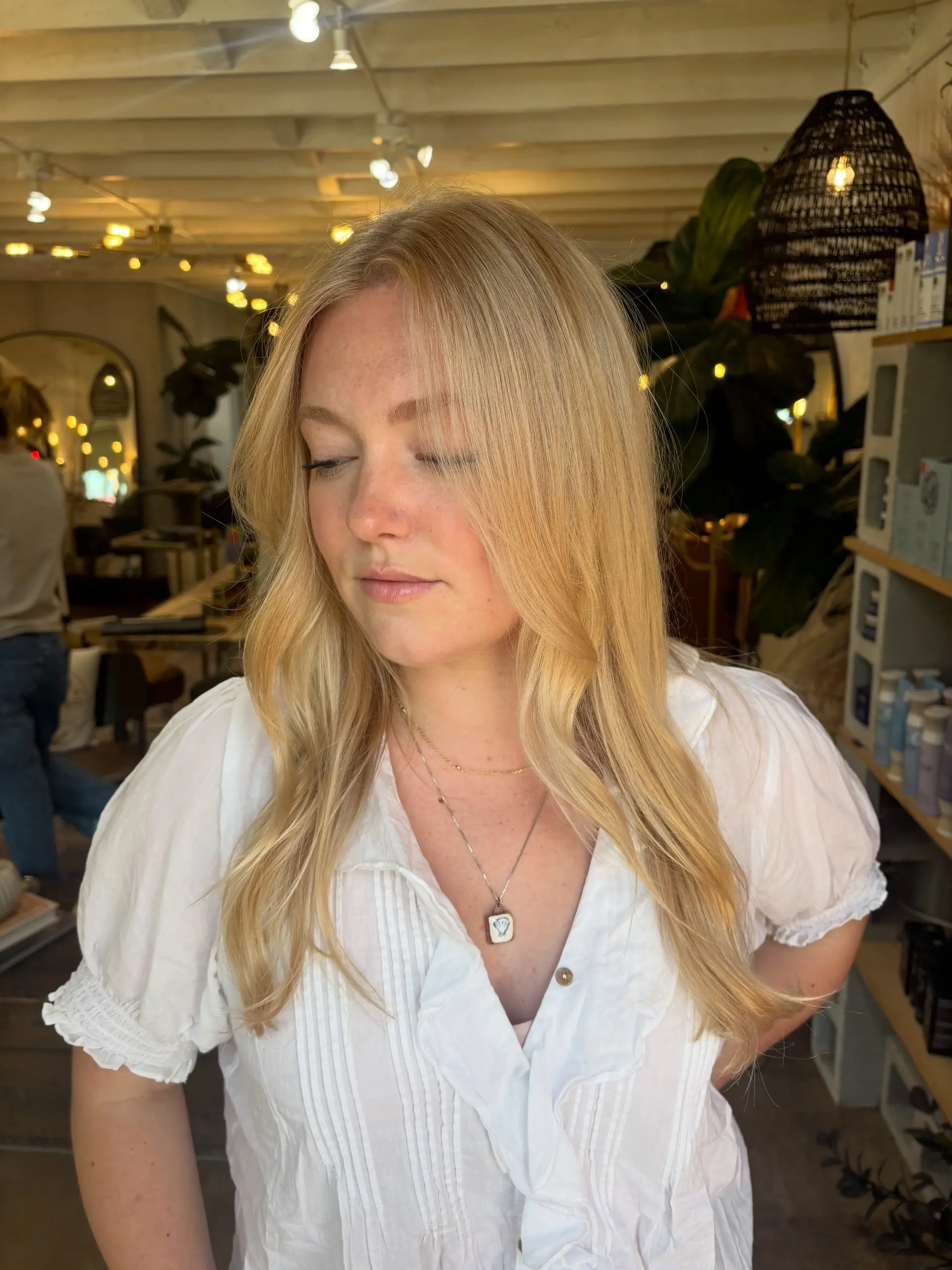 A natural, bright warm blonde with seamless dimensional highlights styled in soft, face-framing waves. 1