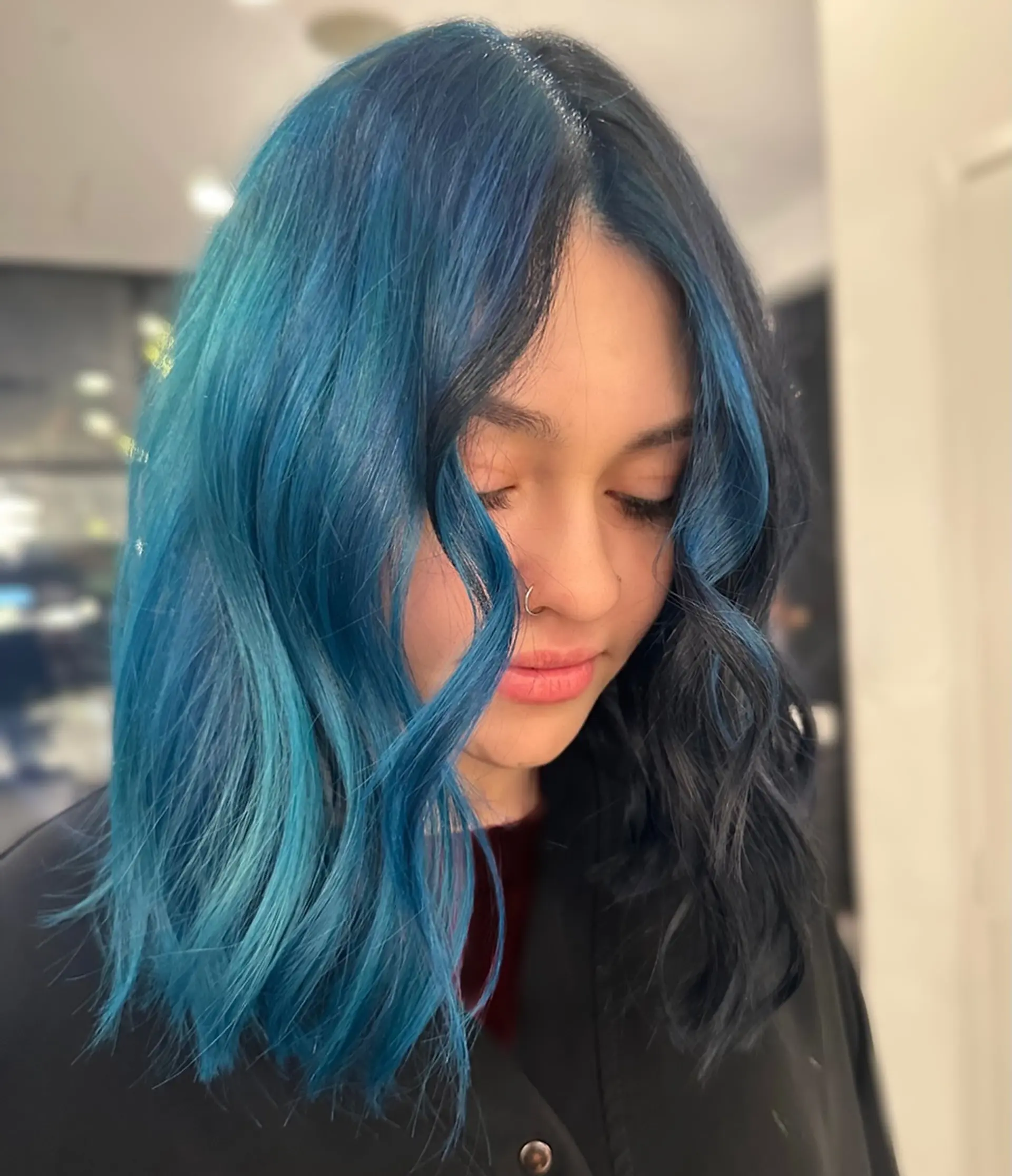 A vibrant split-dye style featuring deep black on one half and electric blue on the other, styled with opposite-color face-framing money pieces in loose waves. 1