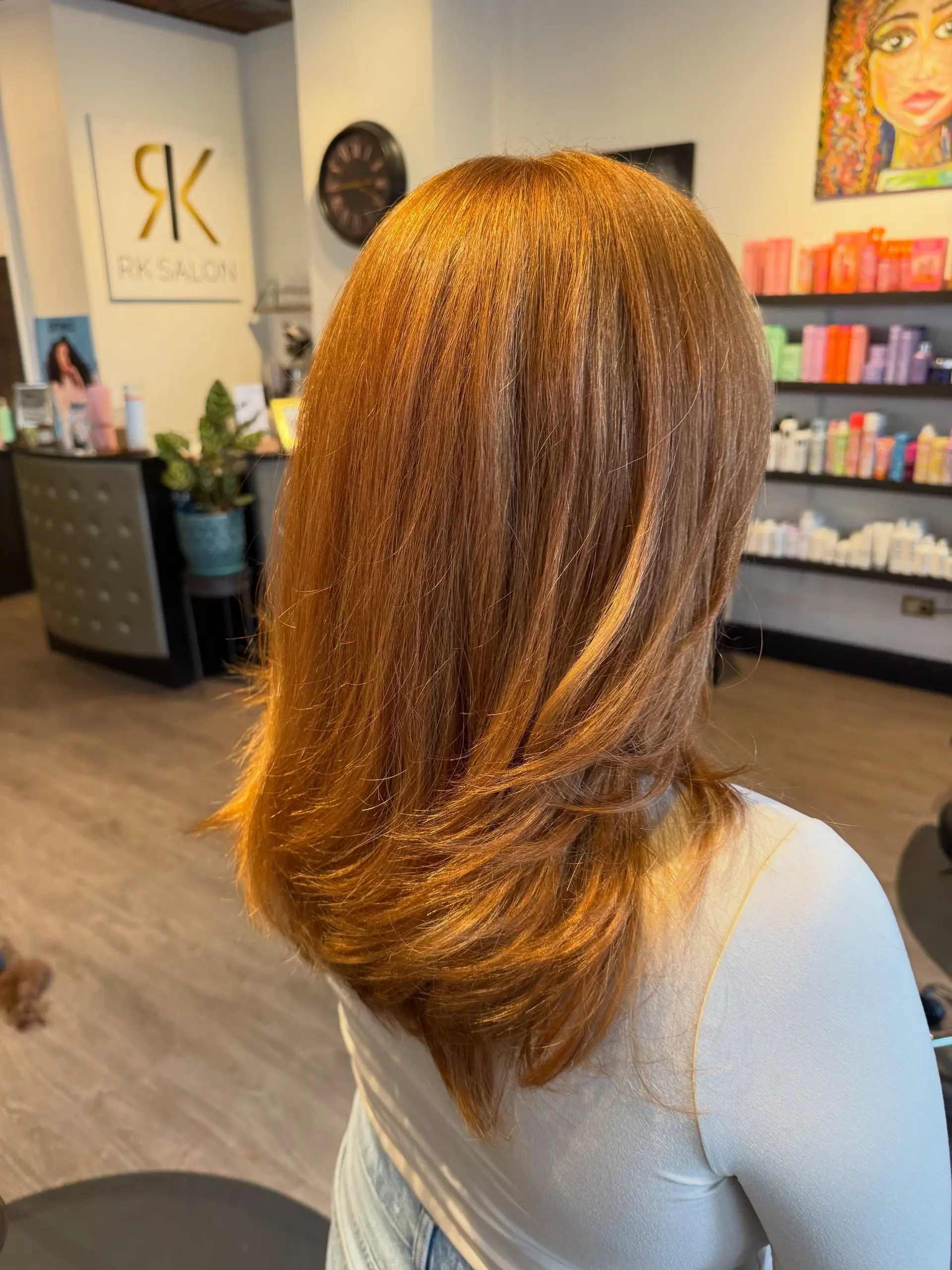 A long, dimensional warm copper haircut featuring soft face-framing layers and ends styled with a gentle outward curl. 1