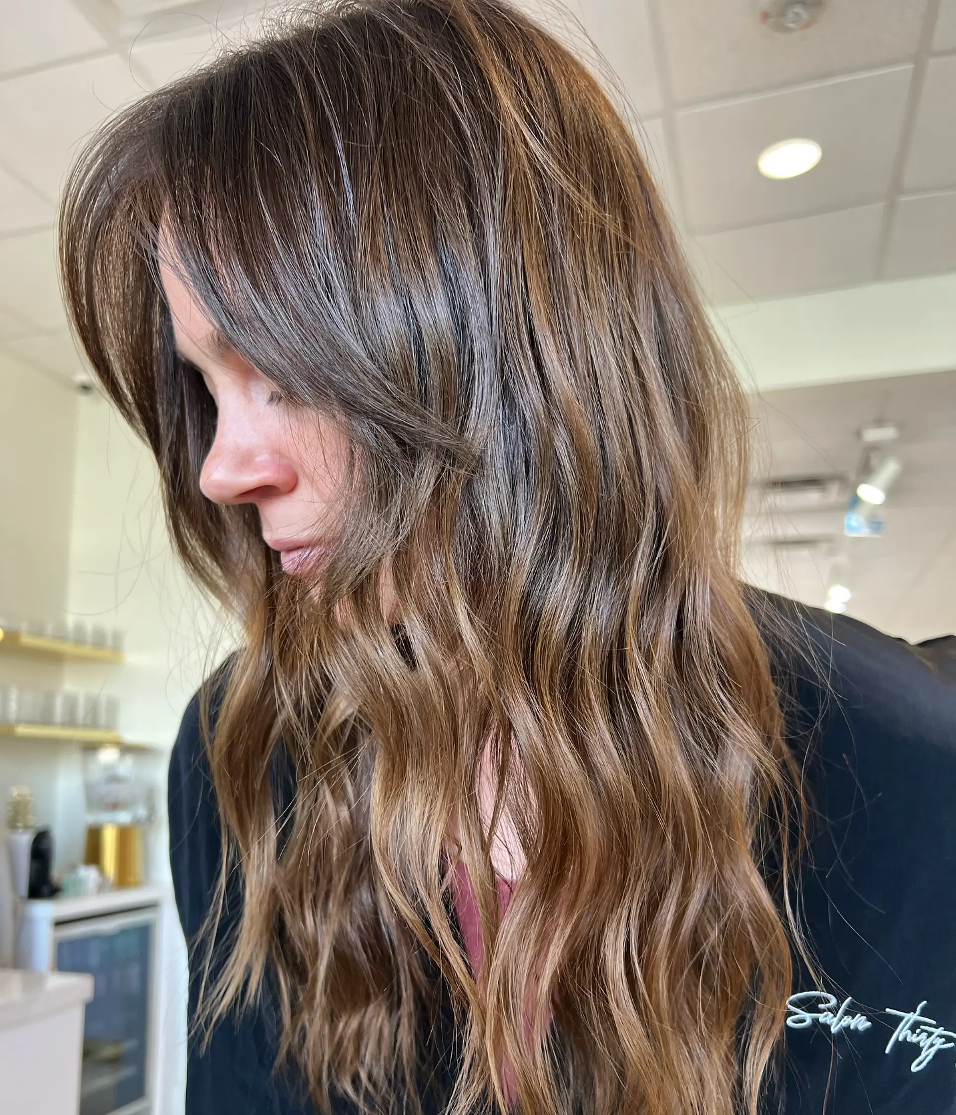 Long, dimensional brunette hair styled in loose, soft waves with subtle face-framing layers and a glossy finish. 1