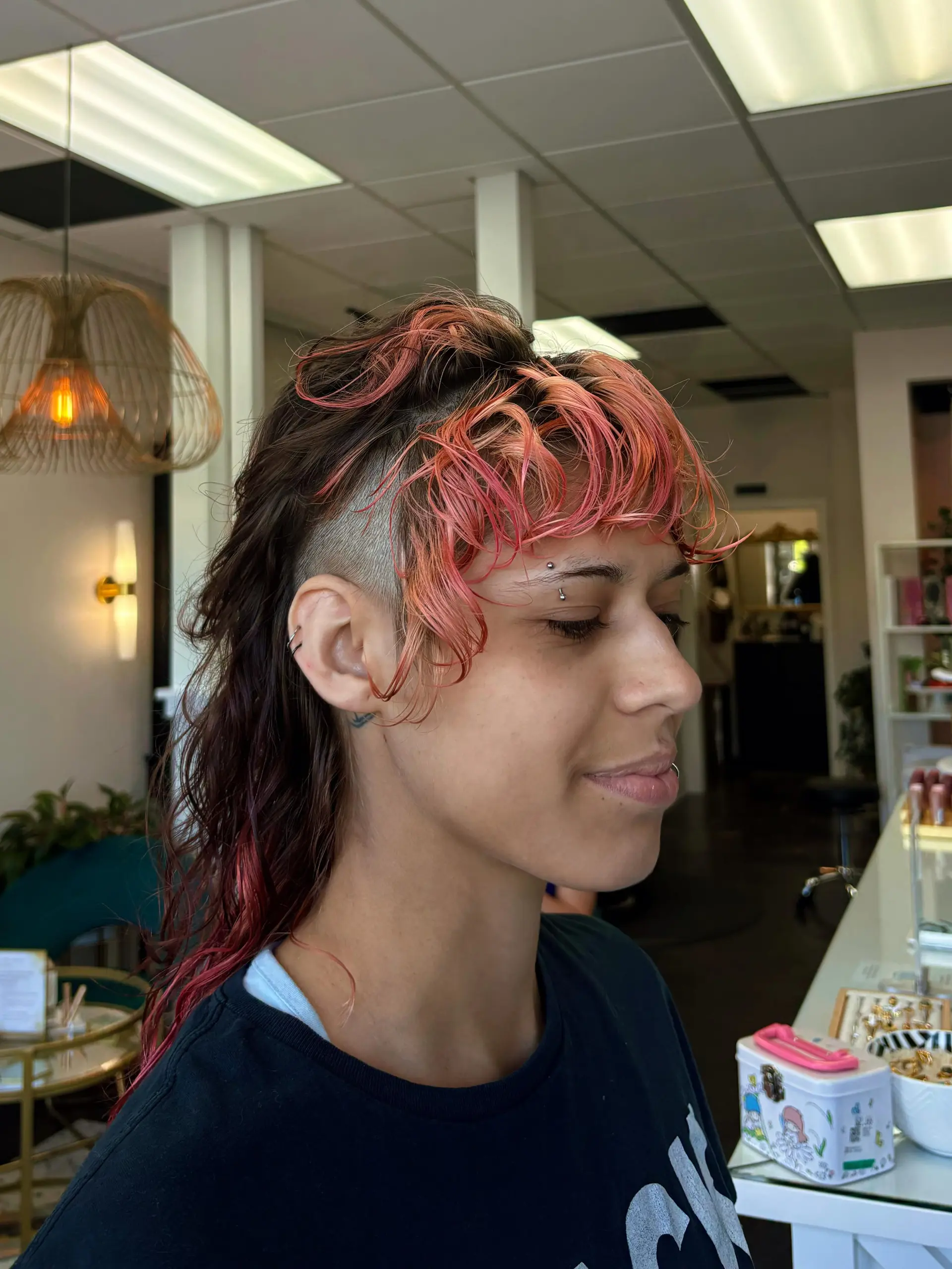 A modern textured mullet featuring closely buzzed undercut sides, a piecy coral-pink fringe, and length at the back. 1
