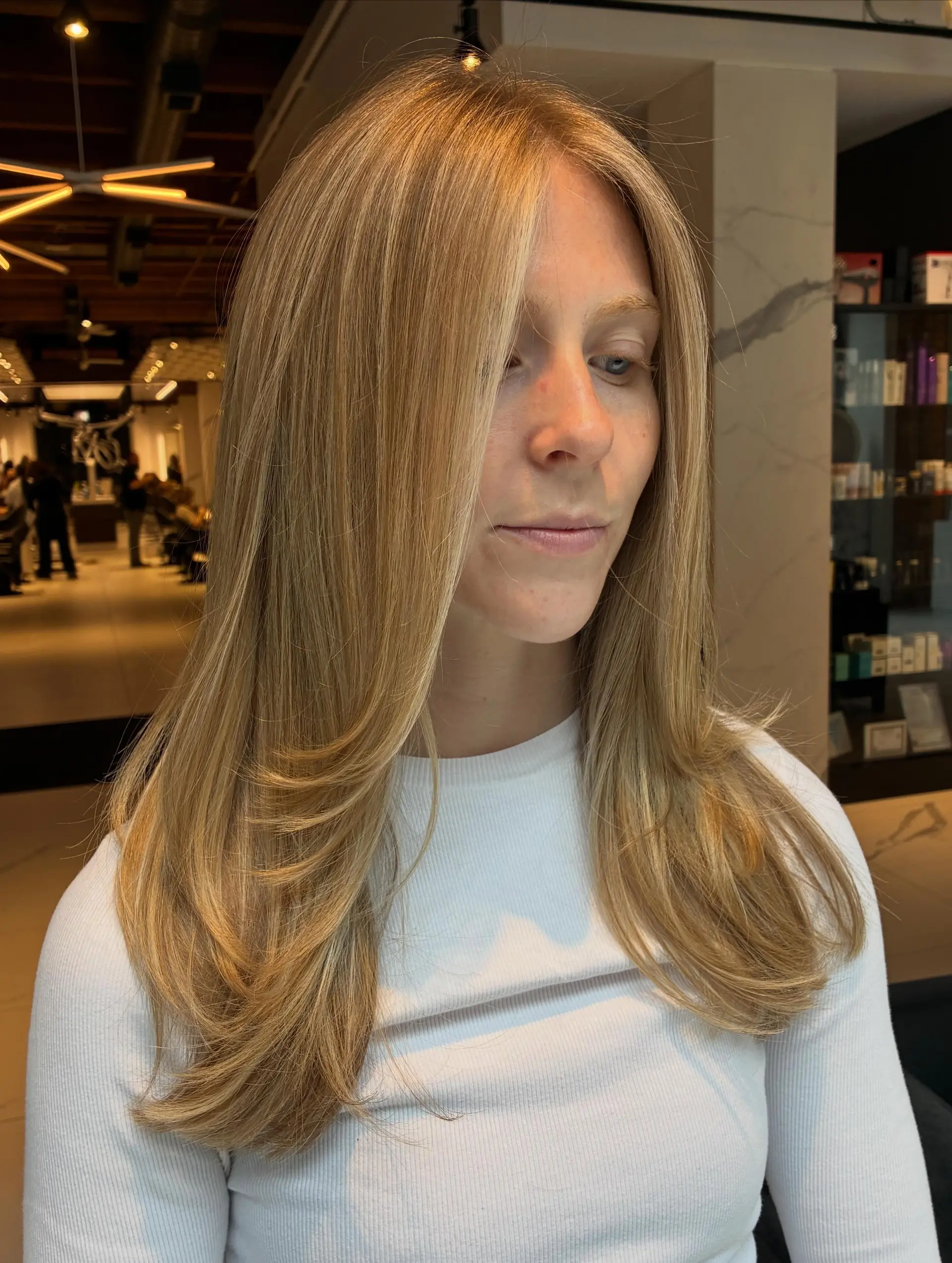 Long golden blonde hair cut with face-framing layers and styled into a sleek blowout with curved ends. 1