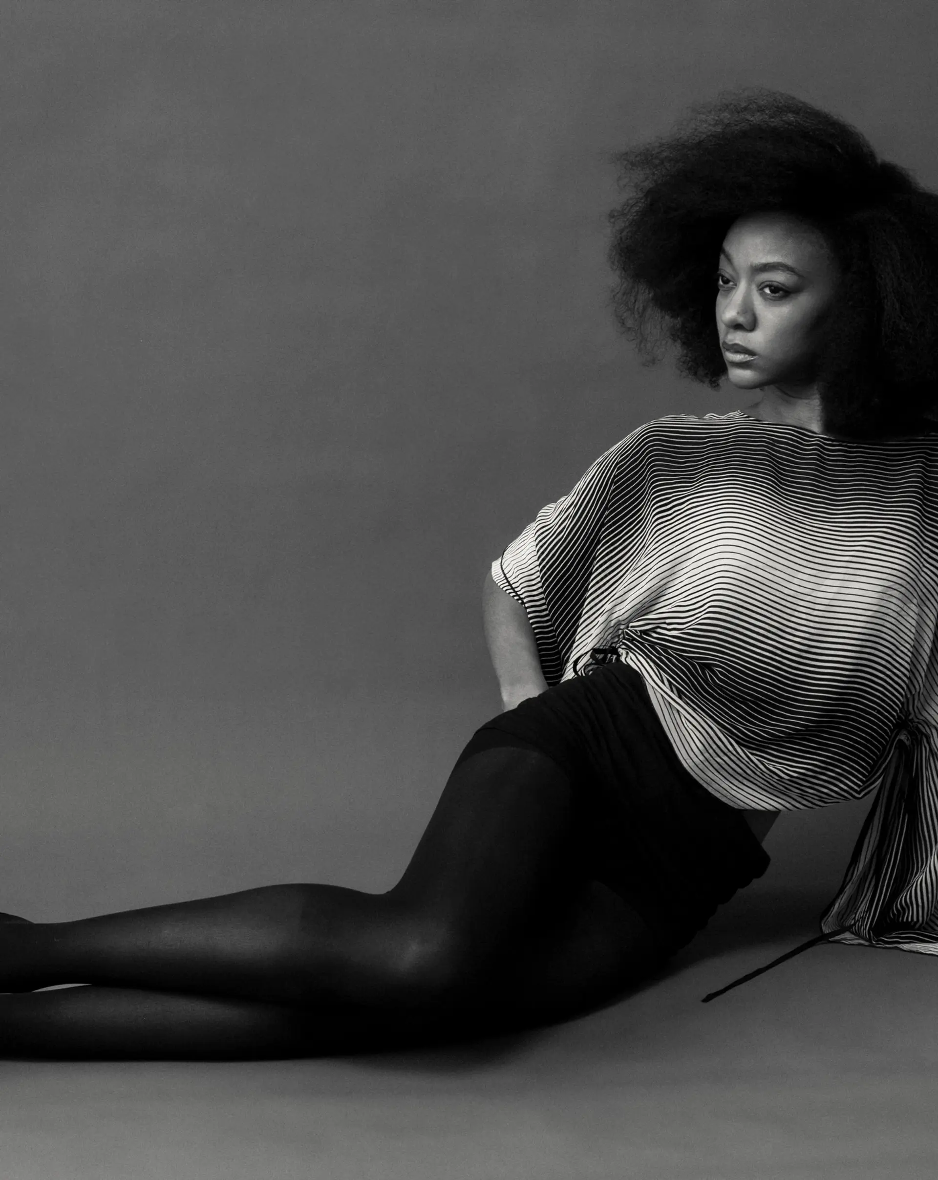 A full, voluminous natural afro hairstyle with defined shape, soft texture, and dramatic editorial volume. 1