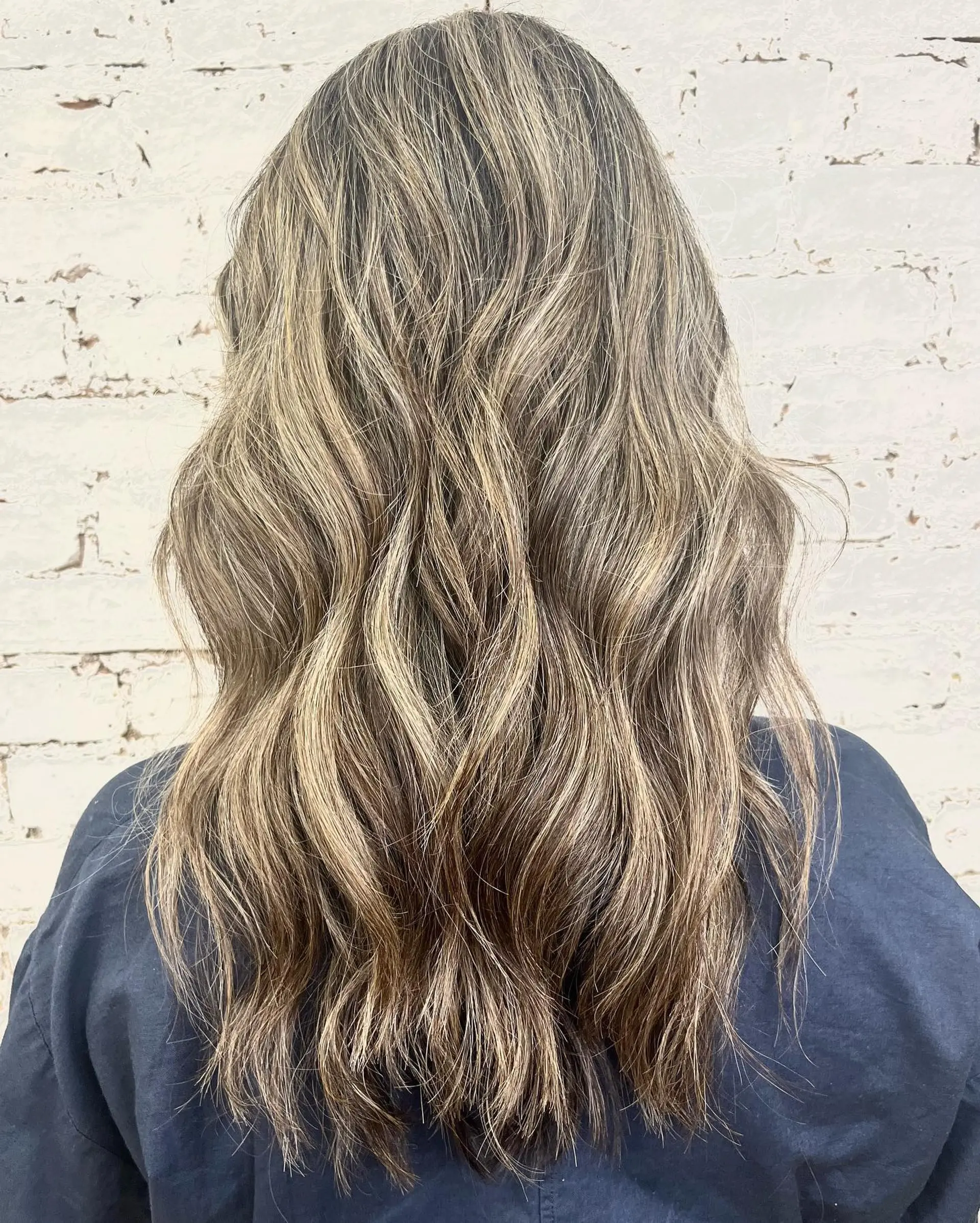 Long wavy hair styled with multidimensional blonde foilyage highlights and subtle lowlights. 1