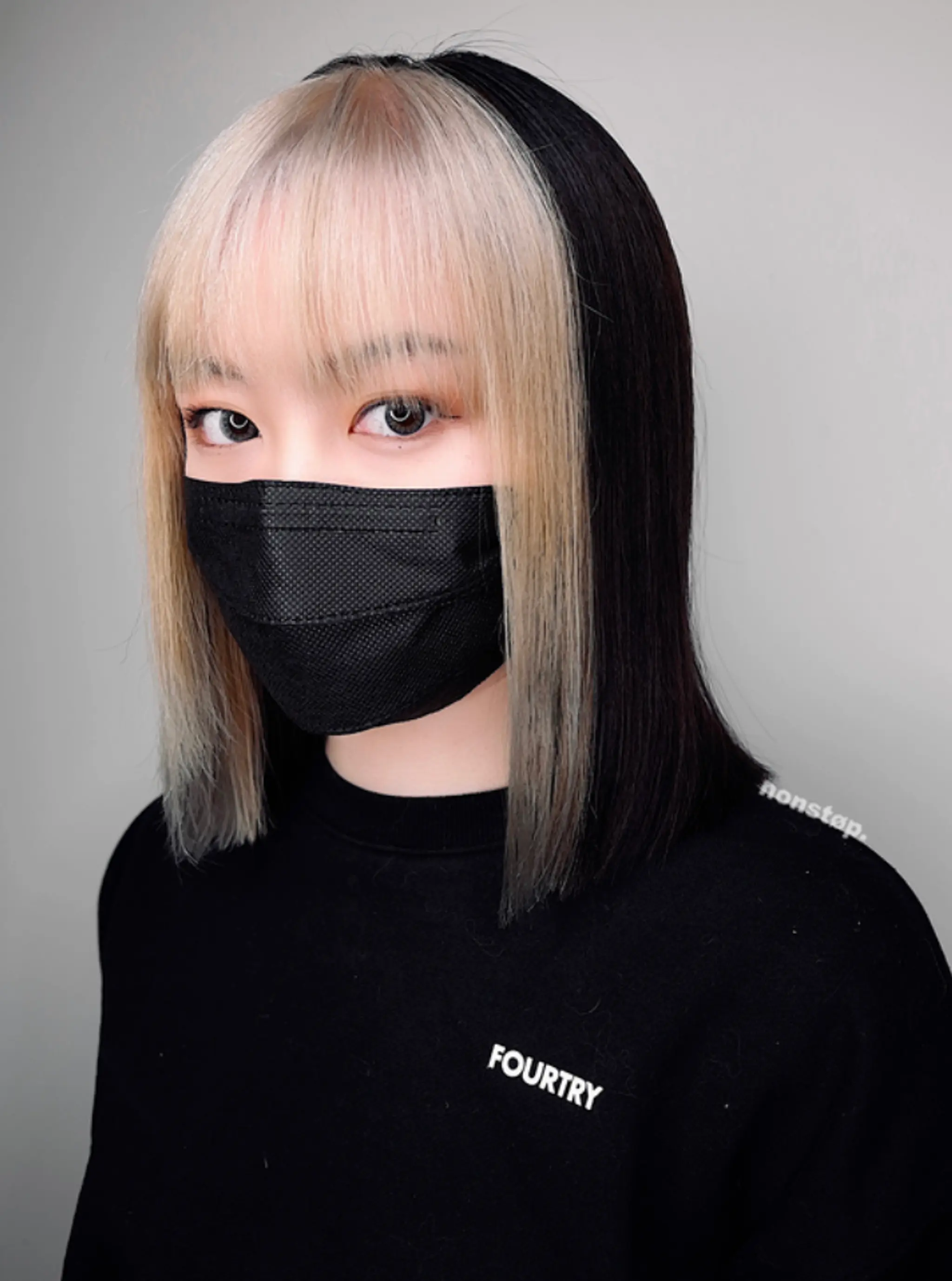 Straight, medium-length hair with a symmetric two-tone color scheme, featuring a blunt fringe that falls just above the eyebrows. The front section is blonde, while the back is black, creating a bold contrast.