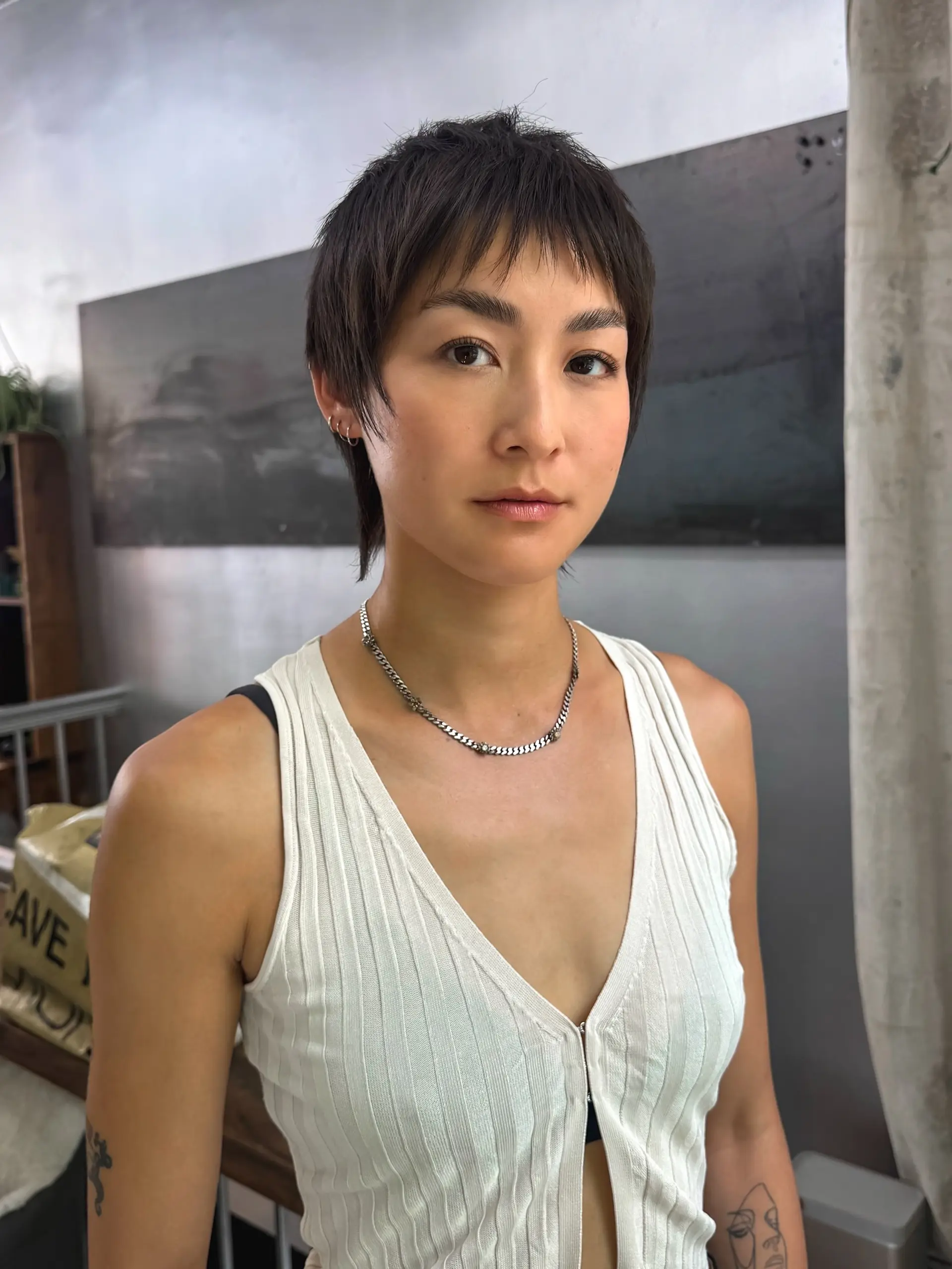 A short and edgy pixie cut with micro bangs, featuring choppy layers and a textured finish. 1