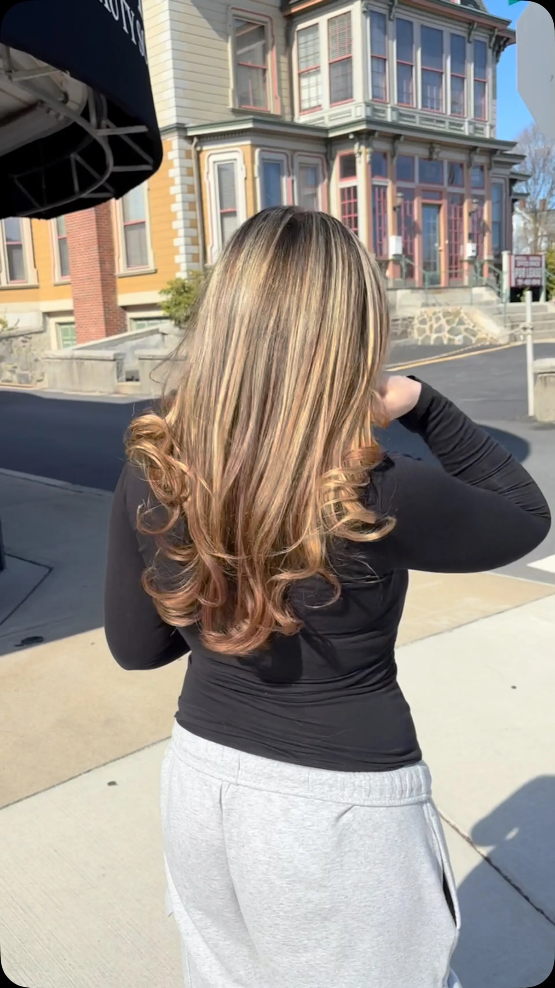 Long hair featuring warm golden highlights, styled into a smooth blowout with bouncy curled ends. 1