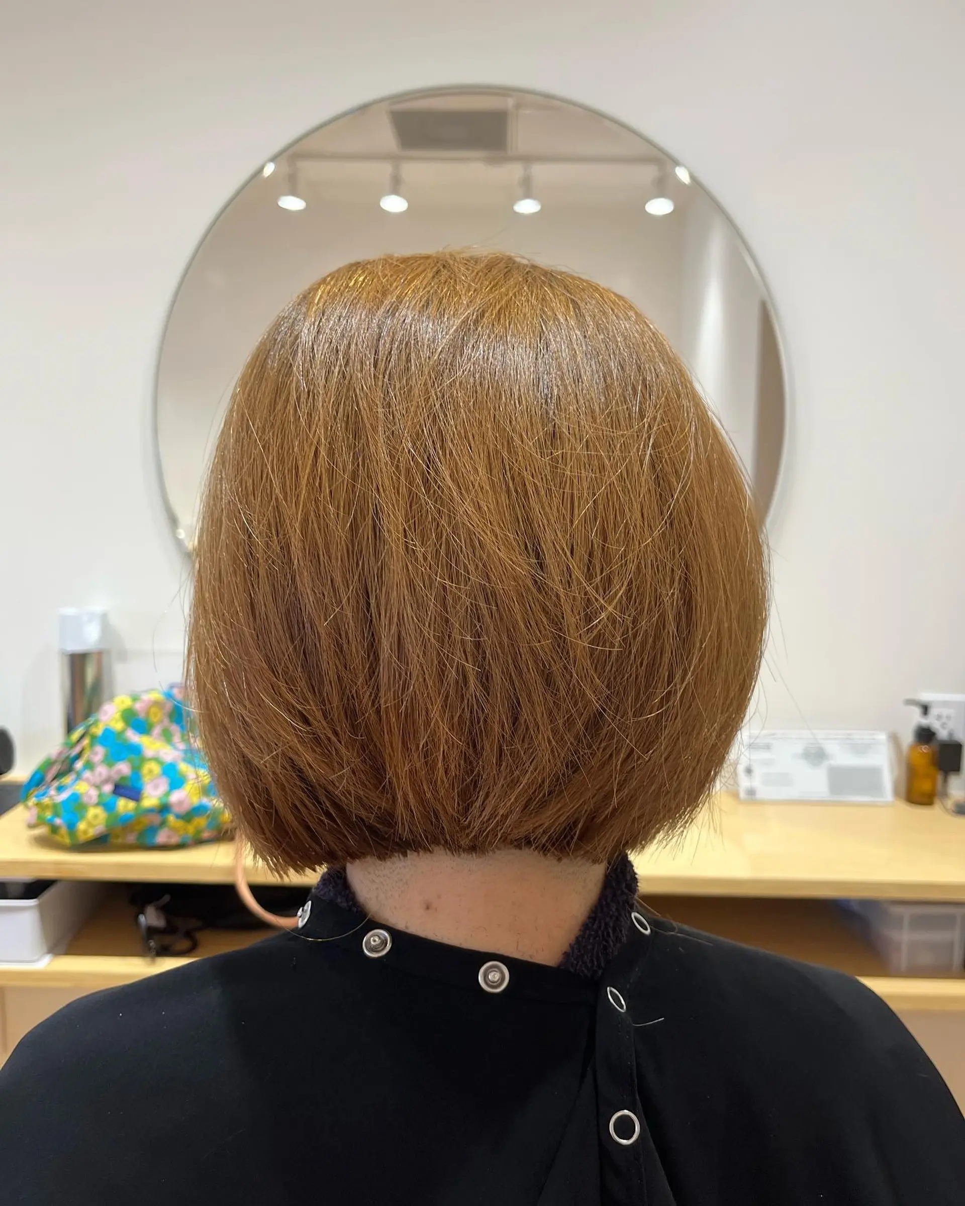 A clean, blunt short bob cut right at the nape of the neck in a warm golden beige tone. 1