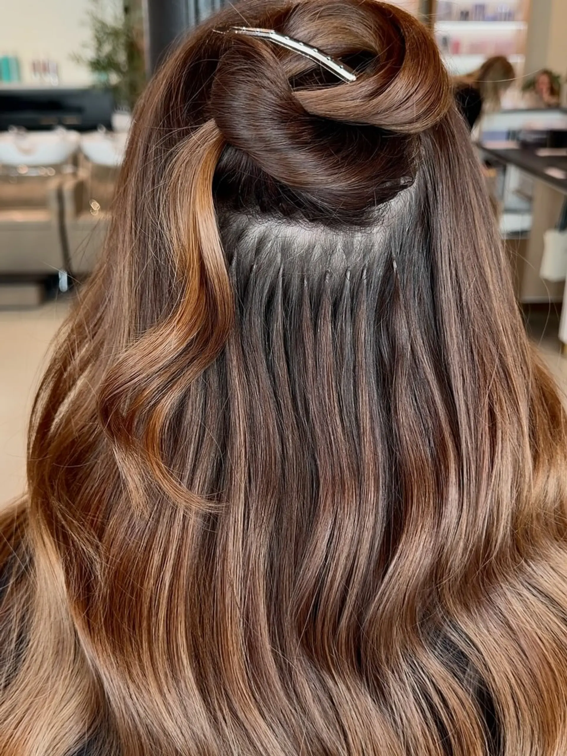 Long brunette hair with warm highlights clipped up to display micro K-tip extension bonds. 1