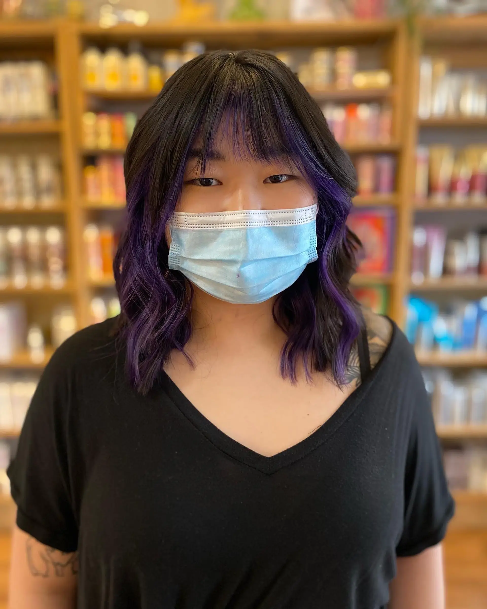 Medium length wavy hair with purple balayage highlights and blunt bangs. 1