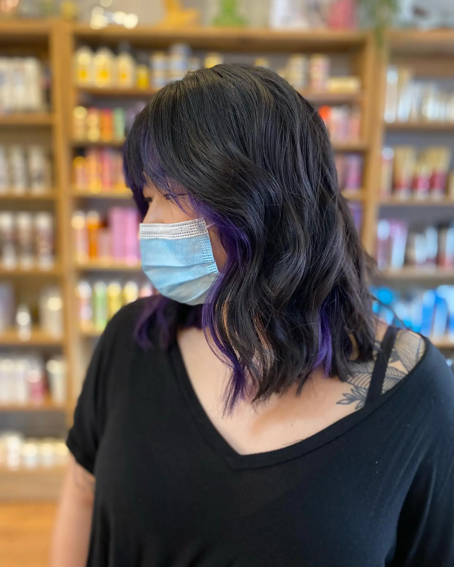 Medium length wavy hair with purple balayage highlights and blunt bangs. 2
