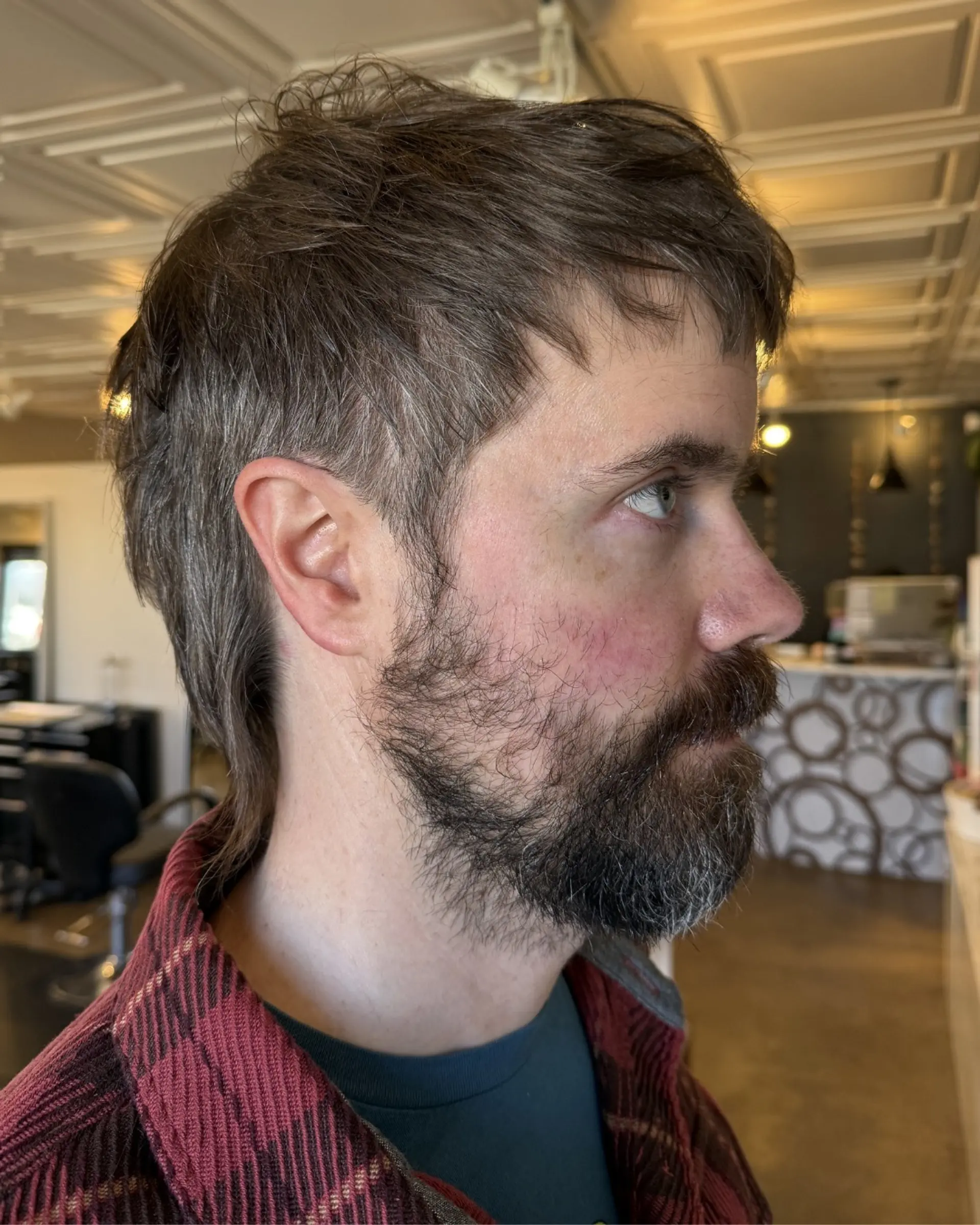 A textured modern mullet featuring a short, piecey fringe, neatly tapered hair around the ears, and extended length down the back. 1