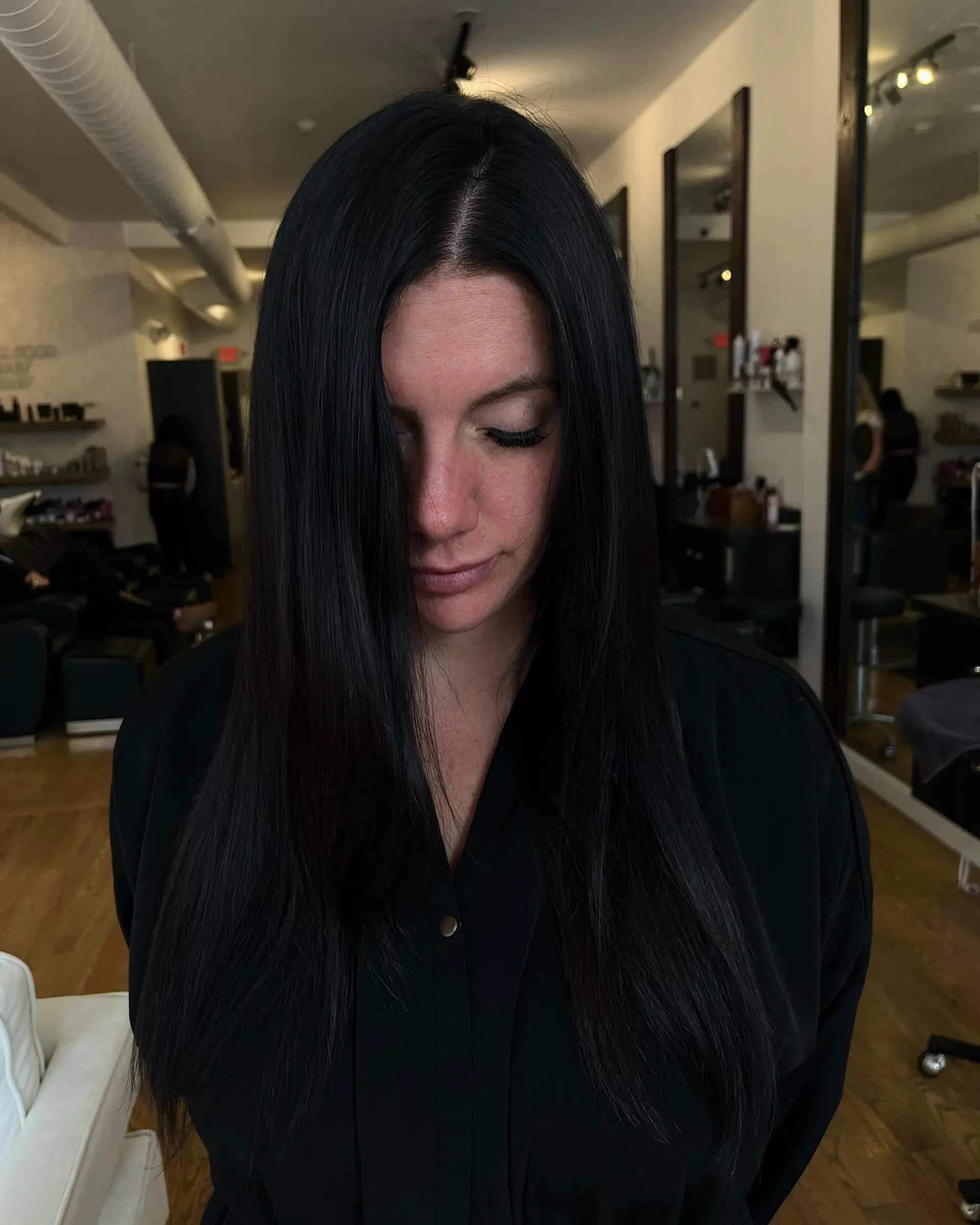 Sleek, straight, long jet black hair parted down the center with seamless volume and length. 1
